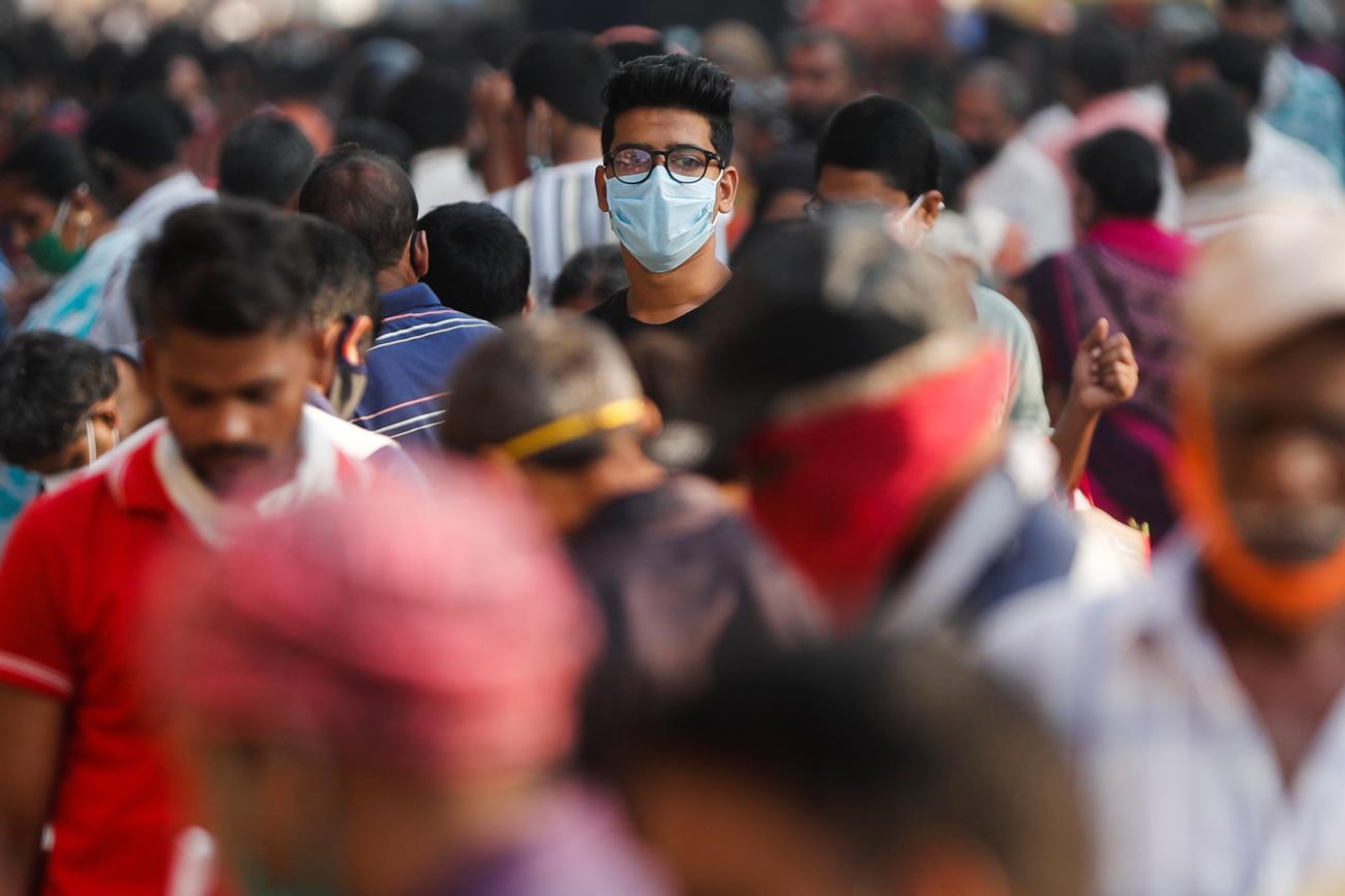 A man wearing a protective mask is seen among people at a crowded market amid the spread of COVID-19.