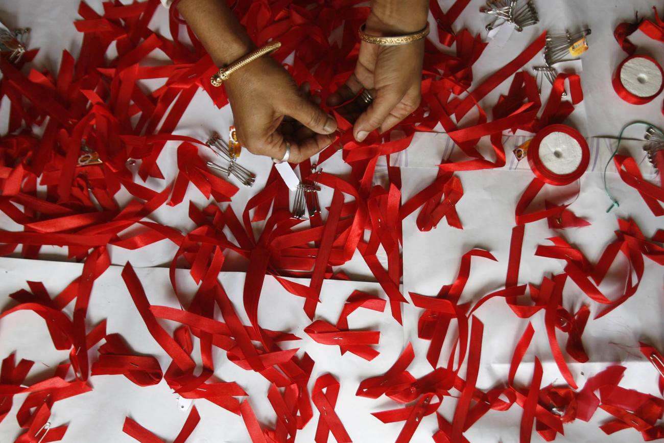 A volunteer suffering from HIV/AIDS makes AIDS symbols with red ribbons during a vaccination program.