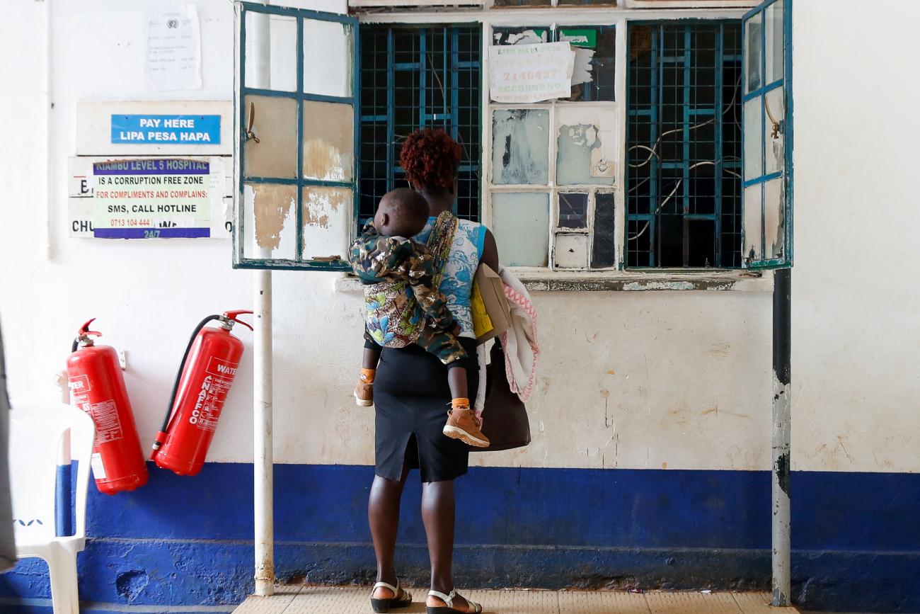 A woman carries her child as they stand at a payment counter.