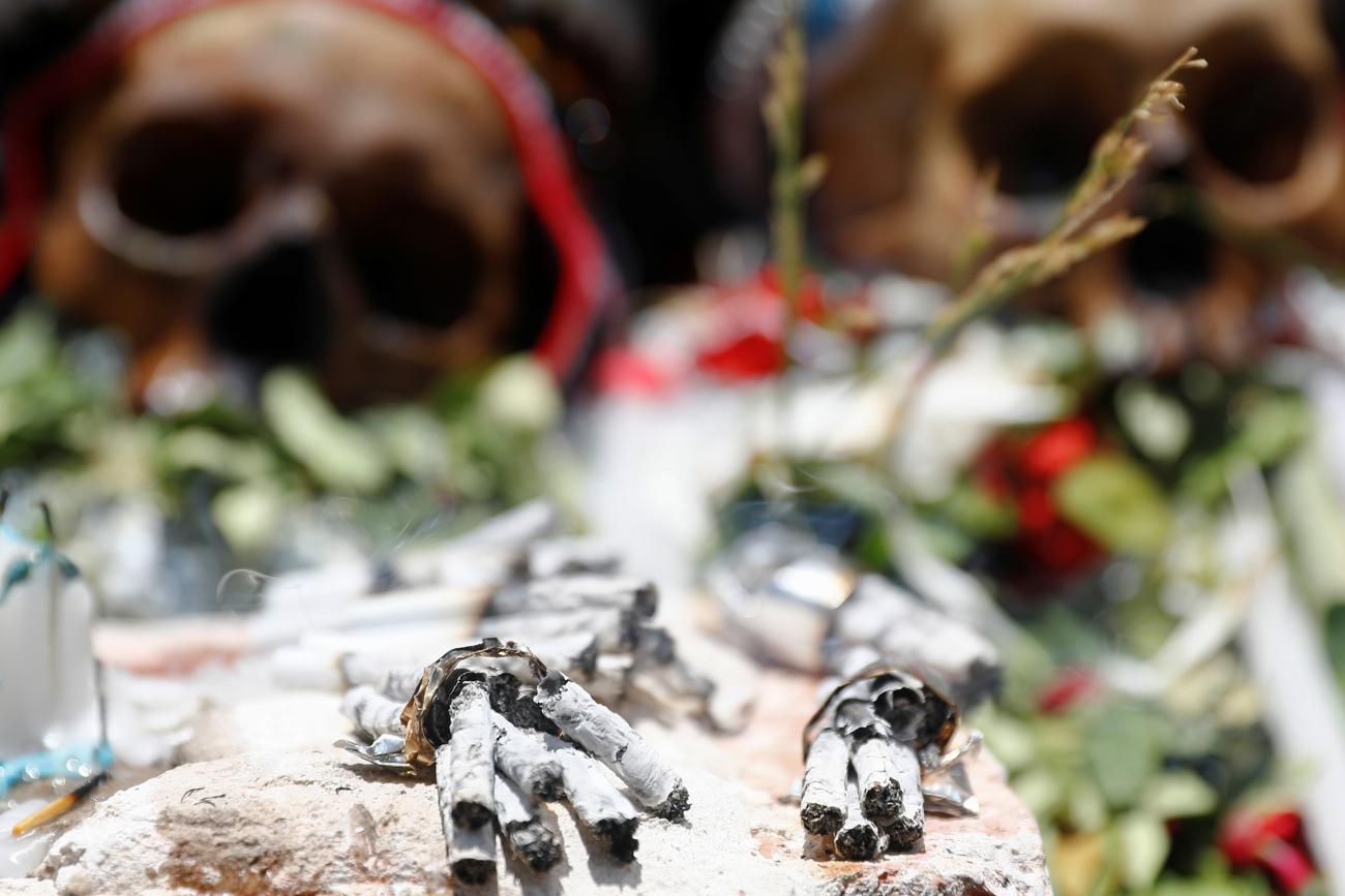 Cigarette butts are seen in front of exhibited skulls during the Day of Skulls celebrations in La Paz, Bolivia November 8, 2019. The photo shows two human skulls laid out with flowers in a ceremonial way with a number of burned cigarettes in the foreground. REUTERS/Kai Pfaffenbach