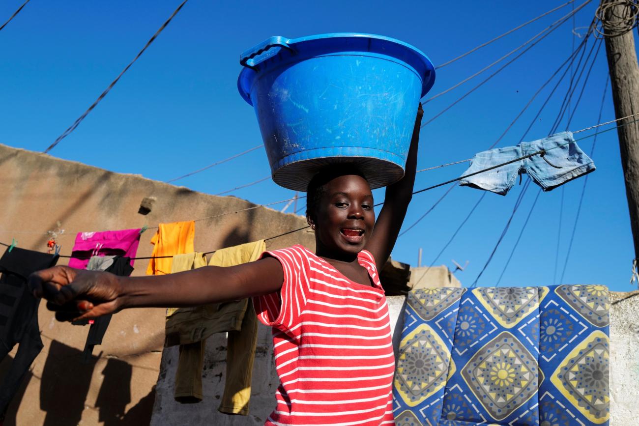 A girl carries a bucket with laundry on her head while heading home as the spread of the coronavirus disease continues, in Yoff neighbourhood, Dakar, Senegal on January 26, 2021.