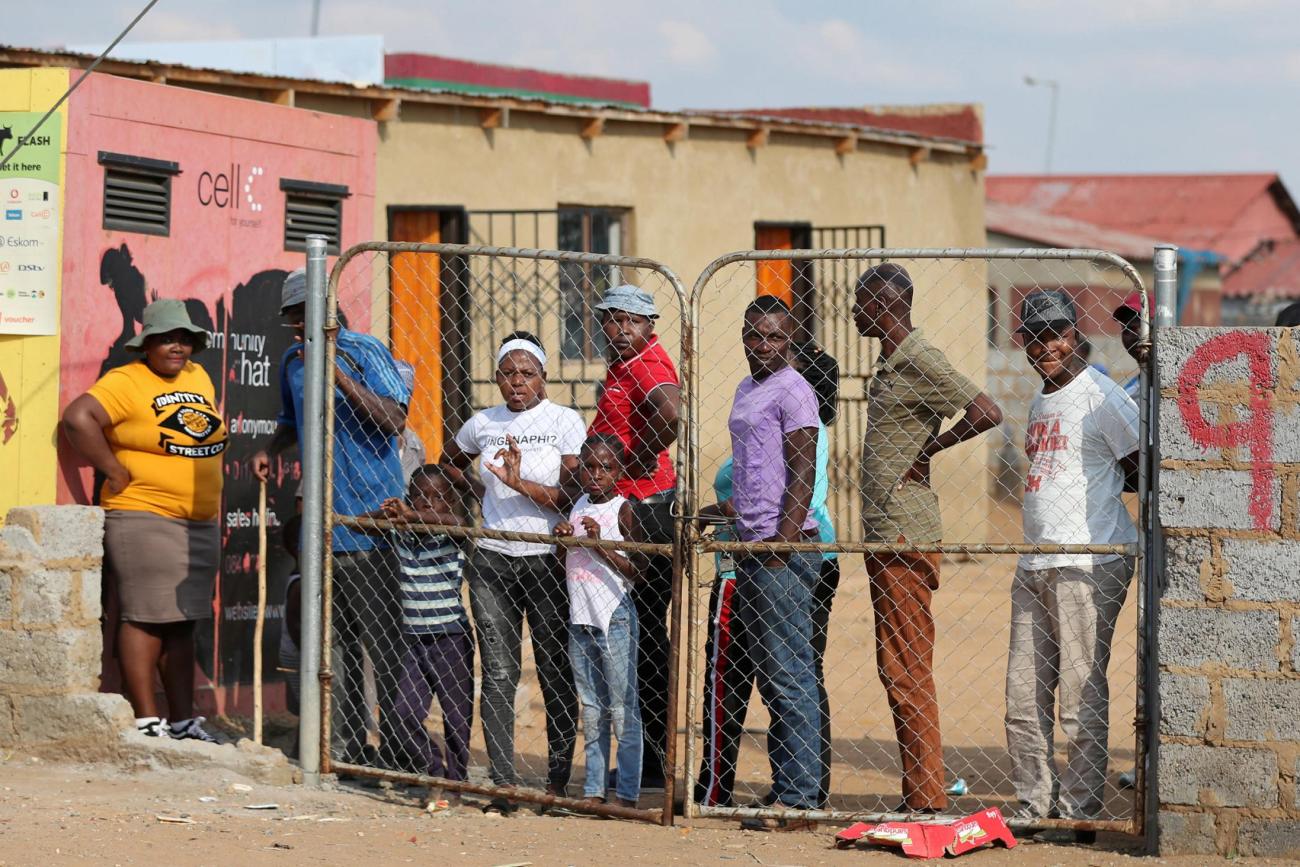 Residents look from behind a closed gate as members of the military patrol during a nationwide lockdown aimed at limiting the spread of novel coronavirus. Soweto, South Africa; April 23, 2020
