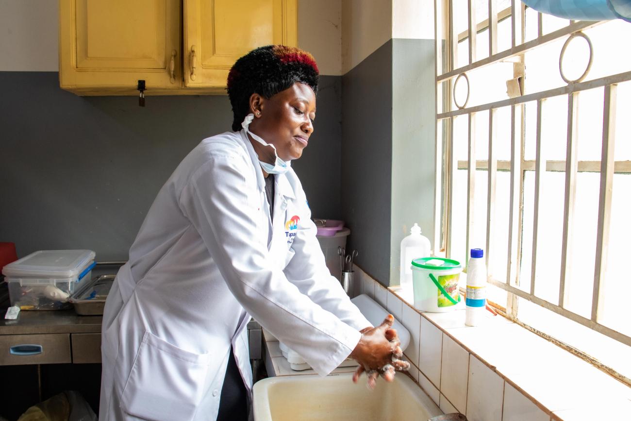 Ddungu Annet, a 39-year-old nursing officer, washes her hands in the labor ward before examining an expectant mother at Nabweru Health Center, Uganda. 