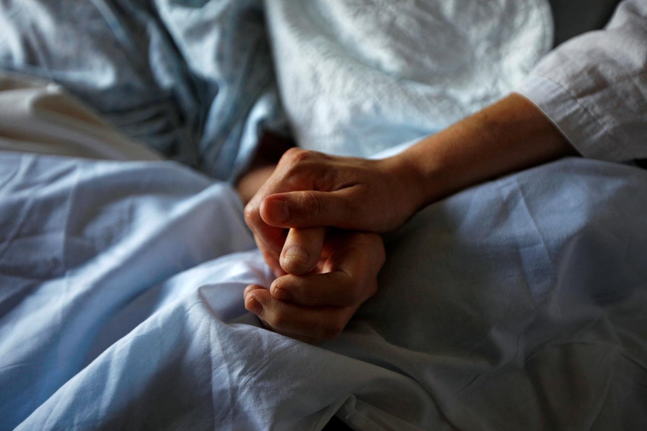 A woman holds the hand of her mother who is dying from cancer during her final hours, at a palliative care hospital, in Winnipeg, Canada, onJuly 24, 2010.