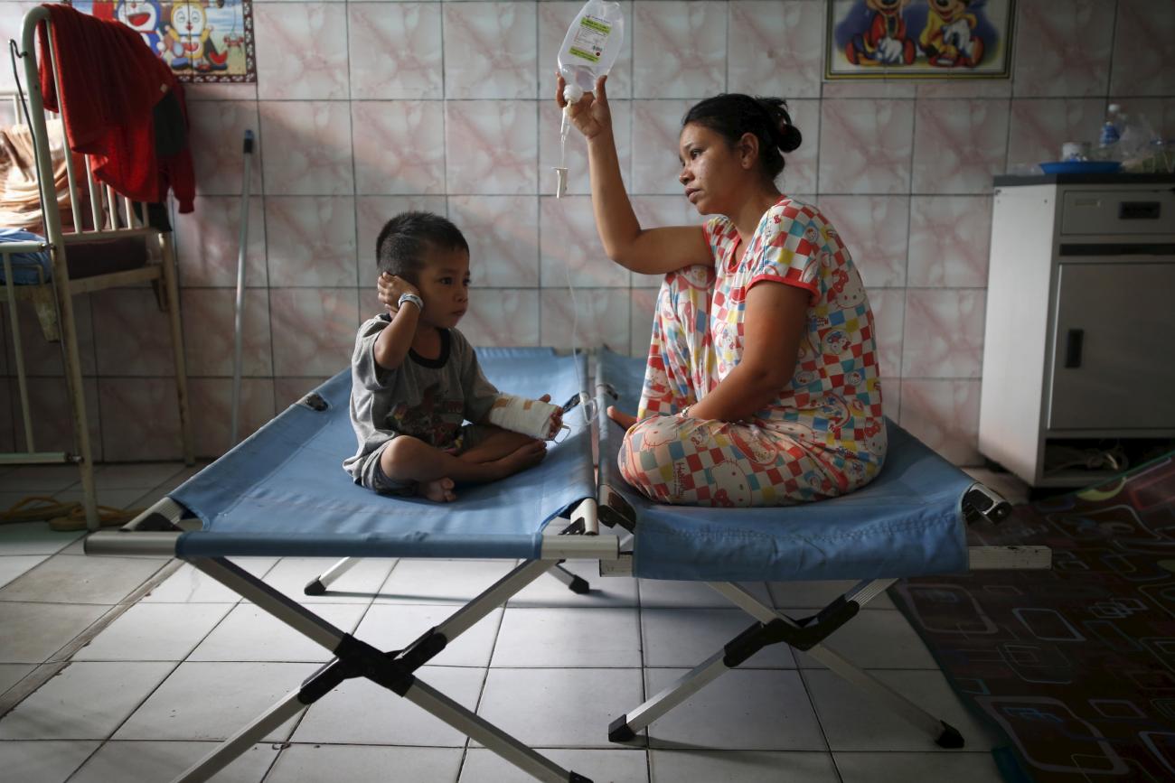 A mother sits with her son who is recovering from a respiratory illness in a hospital in Palangkaraya, Central Kalimantan, Indonesia October 28, 2015