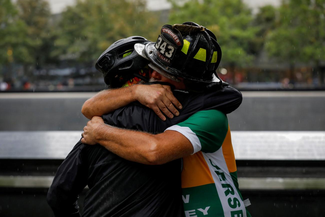 Retired firefighter Darrell Sales of Santa Clara is embraced at the 9/11 Memorial after completing a cross country bicycle ride, named the Bay 2 Brooklyn, to commemorate twentieth anniversary of the September 11 attacks in Manhattan, New York City, September 9, 2021.
