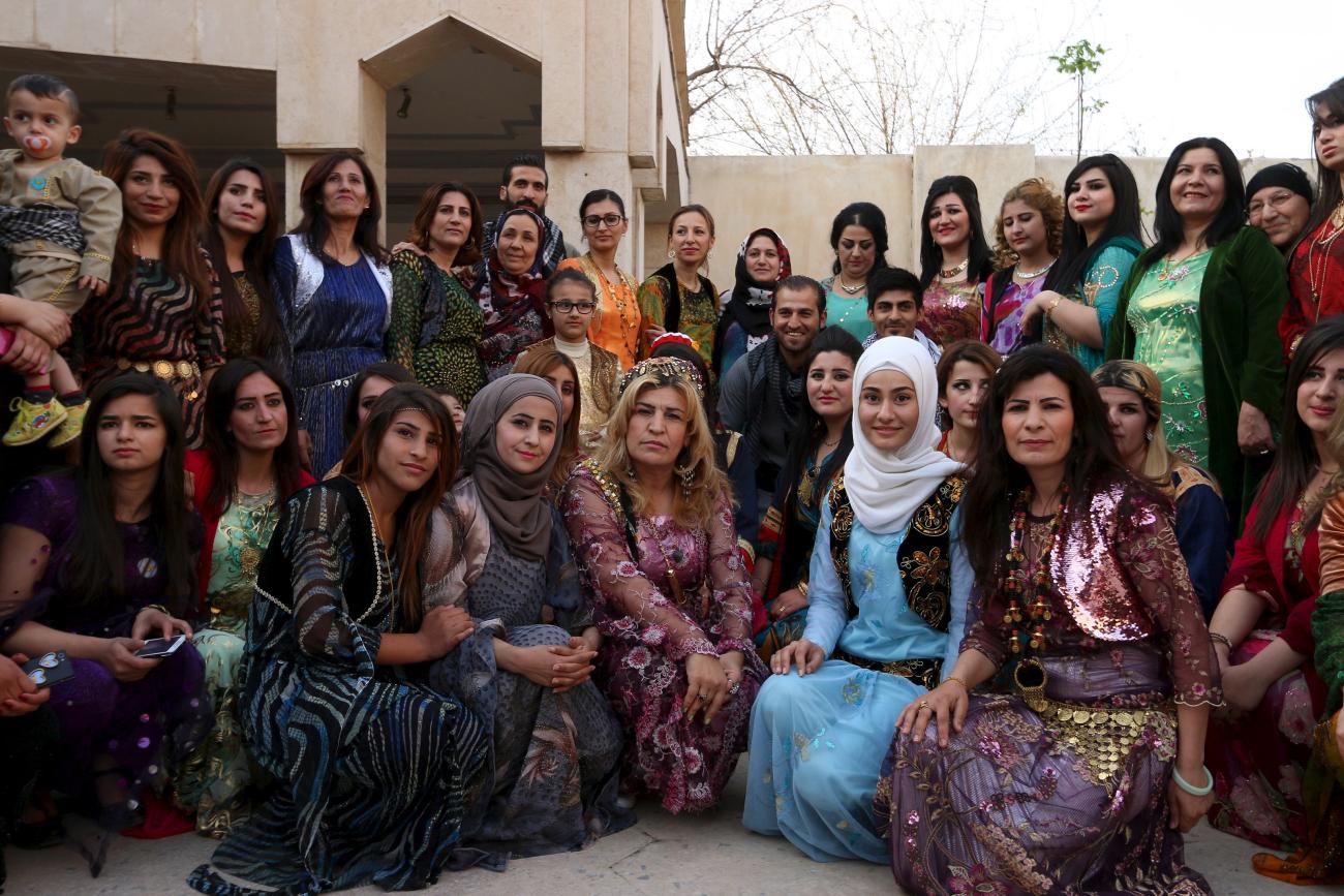 Kurdish women wearing traditional clothes pose for a picture.