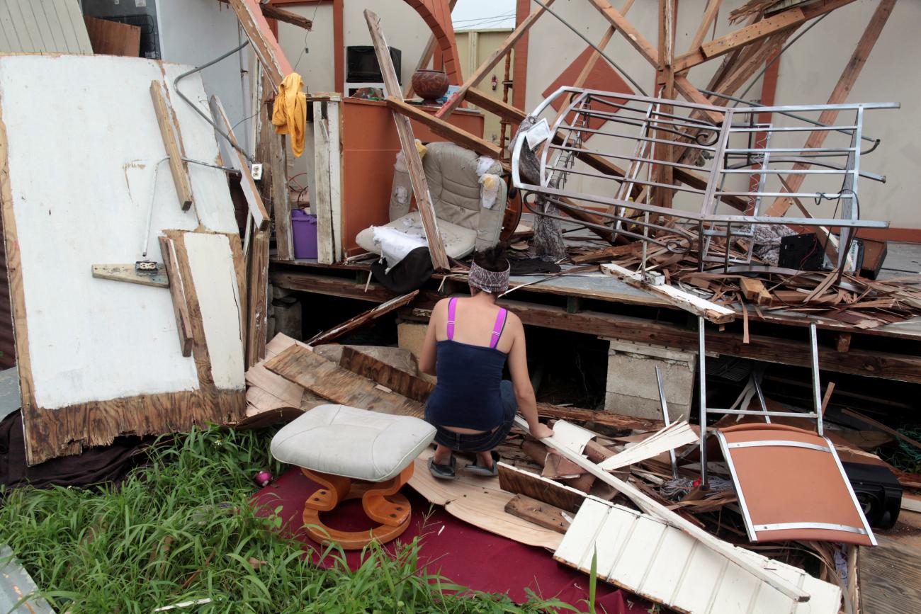 A woman kneels in front of the remains of her home after the area was hit by Hurricane Maria.