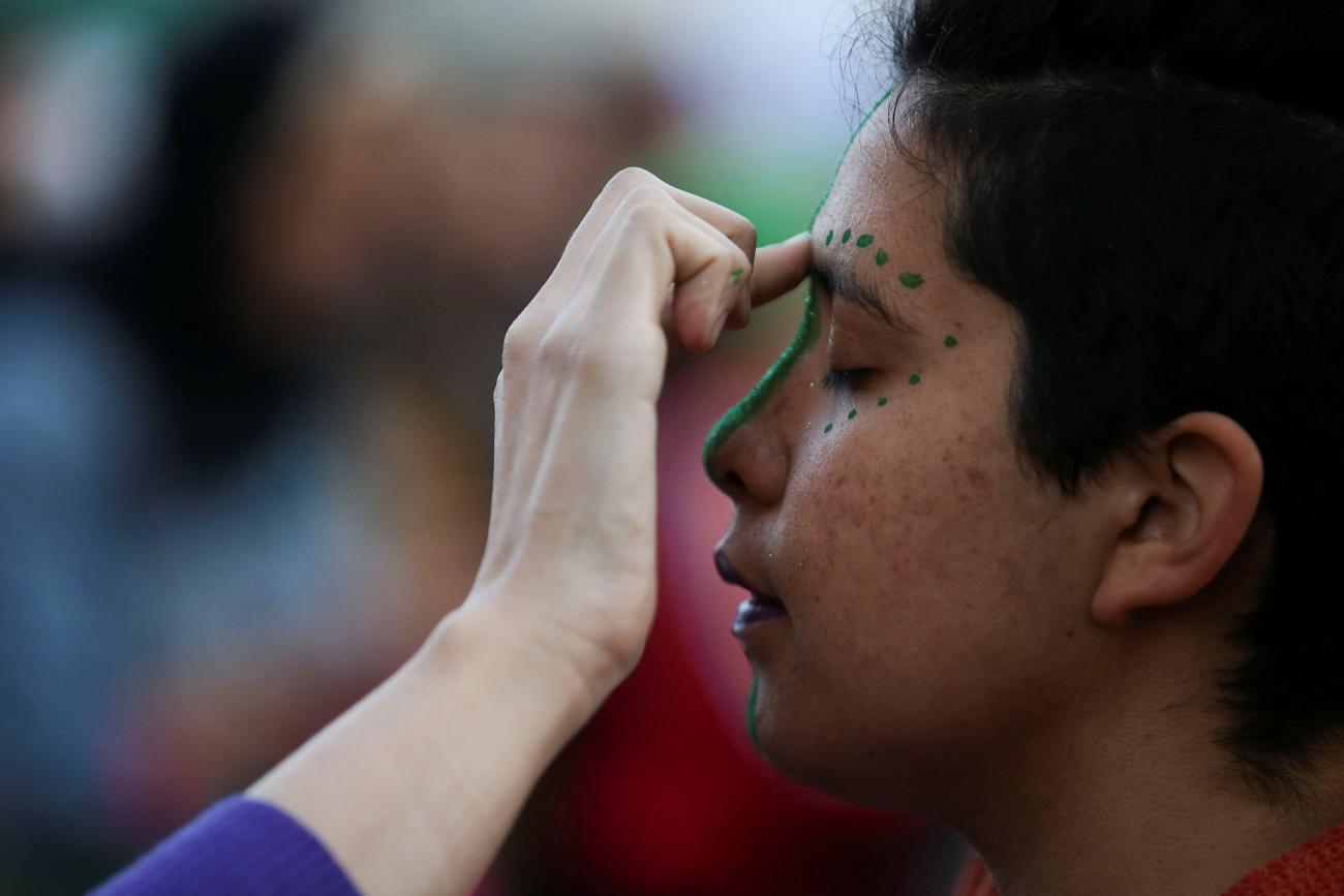 A person gets their face painted to take part in a rally in favor of legalizing abortion.