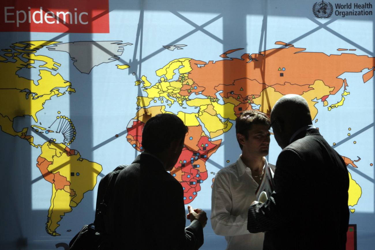 Delegates walk past an information board during the 62nd World Health Assembly at the United Nations European headquarters, in Geneva, Switzerland, on May 18, 2009.