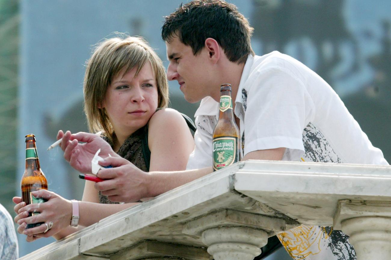 A young couple chat as they drink beer and smoke cigarettes, in Moscow, Russia, on August 8, 2004.