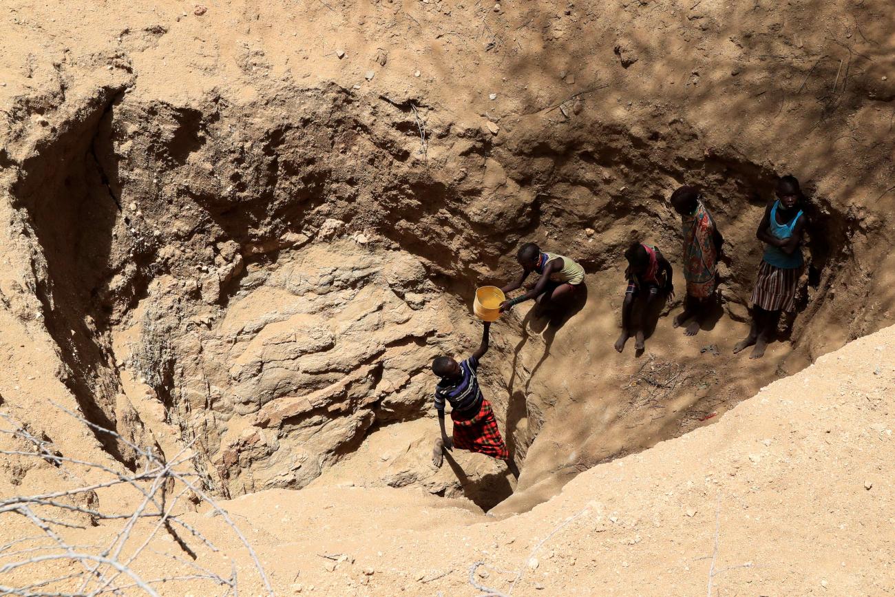 Members of the Turkana pastoralist community affected by the worsening drought due to failed rain seasons, collect water from an open well dug on a dry riverbed, Turkana, Kenya, on September 27, 2022.