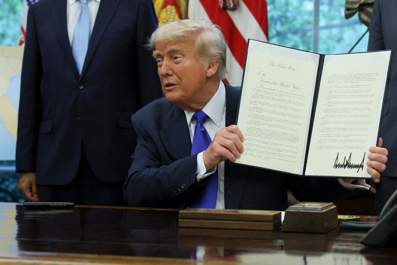 U.S. President Donald Trump shows a signed document as he signs executive orders and proclamations in the Oval Office at the White House, in Washington, DC, on May 5, 2025. 