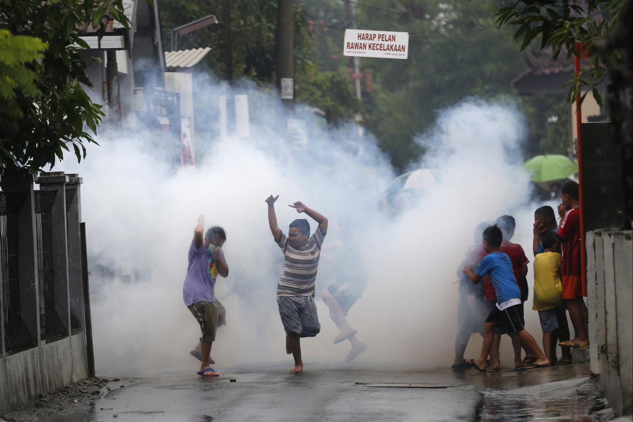 Children watch and play near a worker who is using the traditional method of chemical fogging to kill mosquitoes, in Yogyakarta, Indonesia, on February 5, 2016.