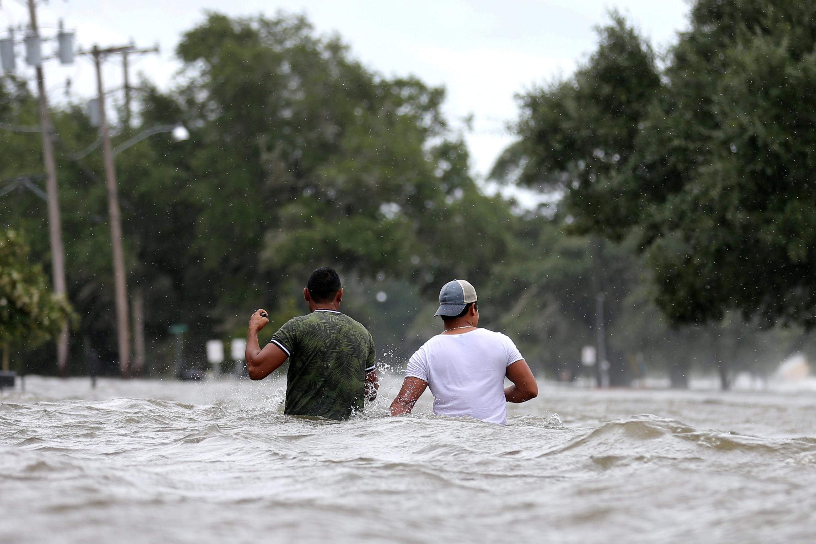 People wade through a flooded street after Hurricane Barry in Mandeville, Louisiana.