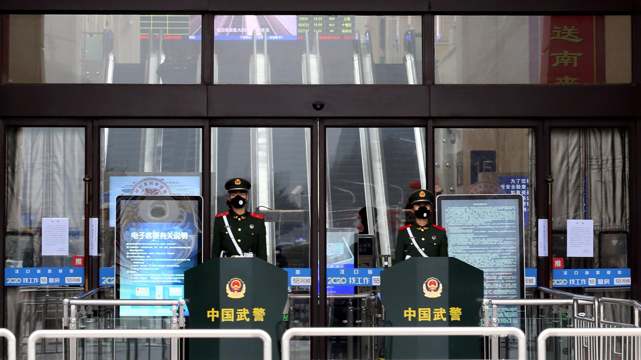 The photo shows the shuttered front of the grand entrance hall to the station with two soldiers wearing face masks out front.