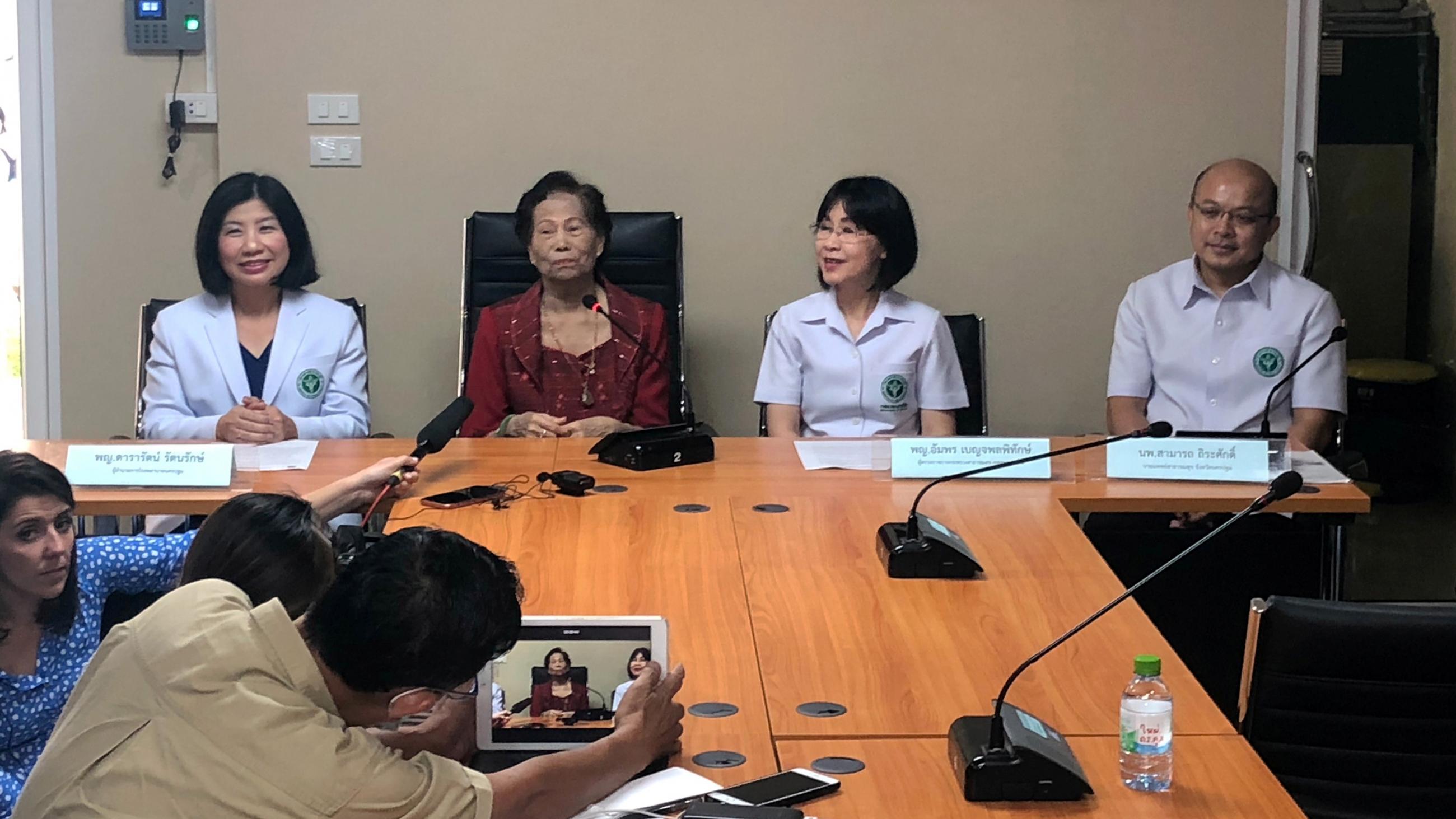 This photo shows a press conference with a smiling survivor in the middle. 