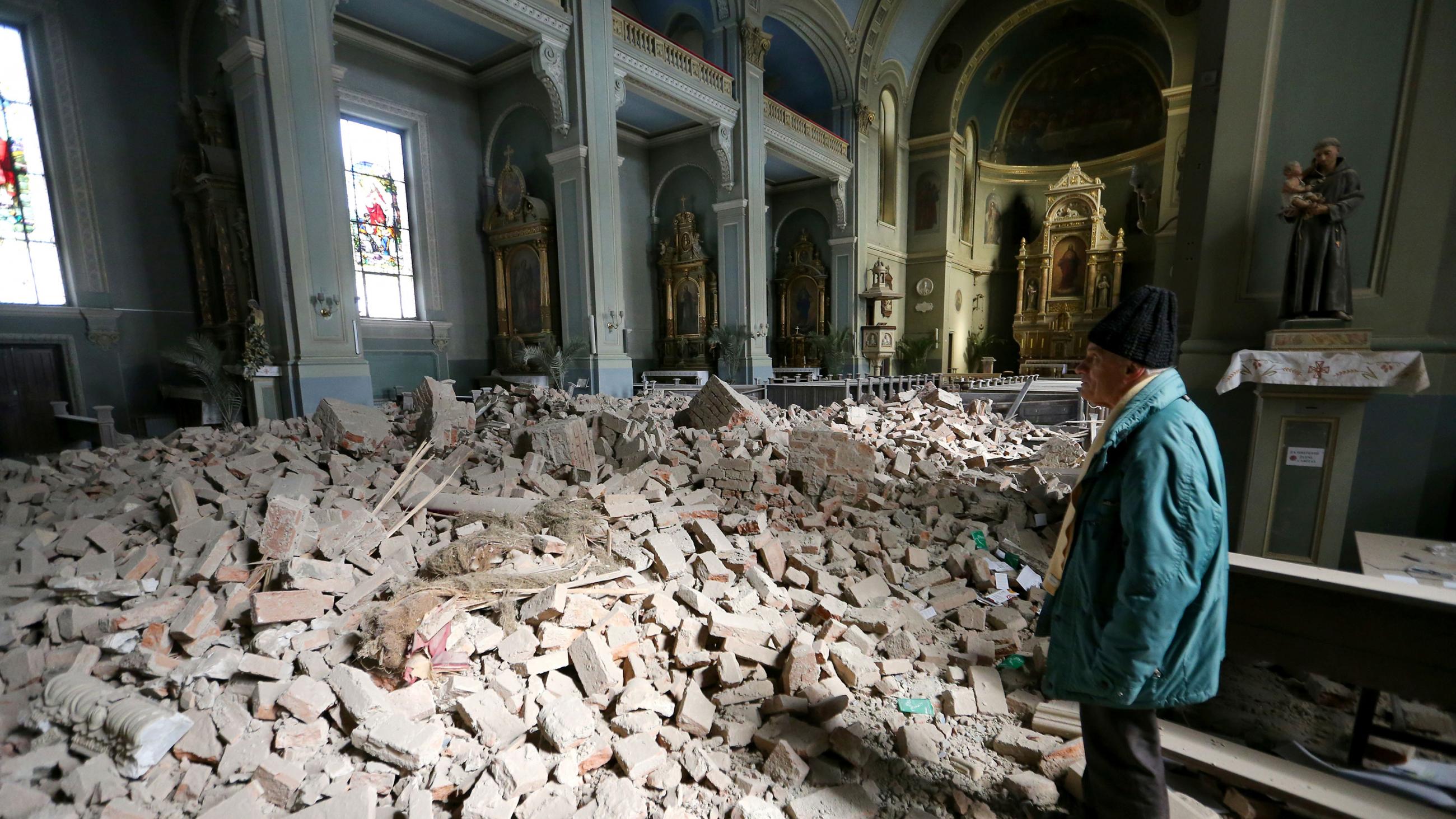 The photo shows the interior of a grand and old church that has undergone a significant amount of damage. The roof still stands but the floor of the church is filled with rubble. 