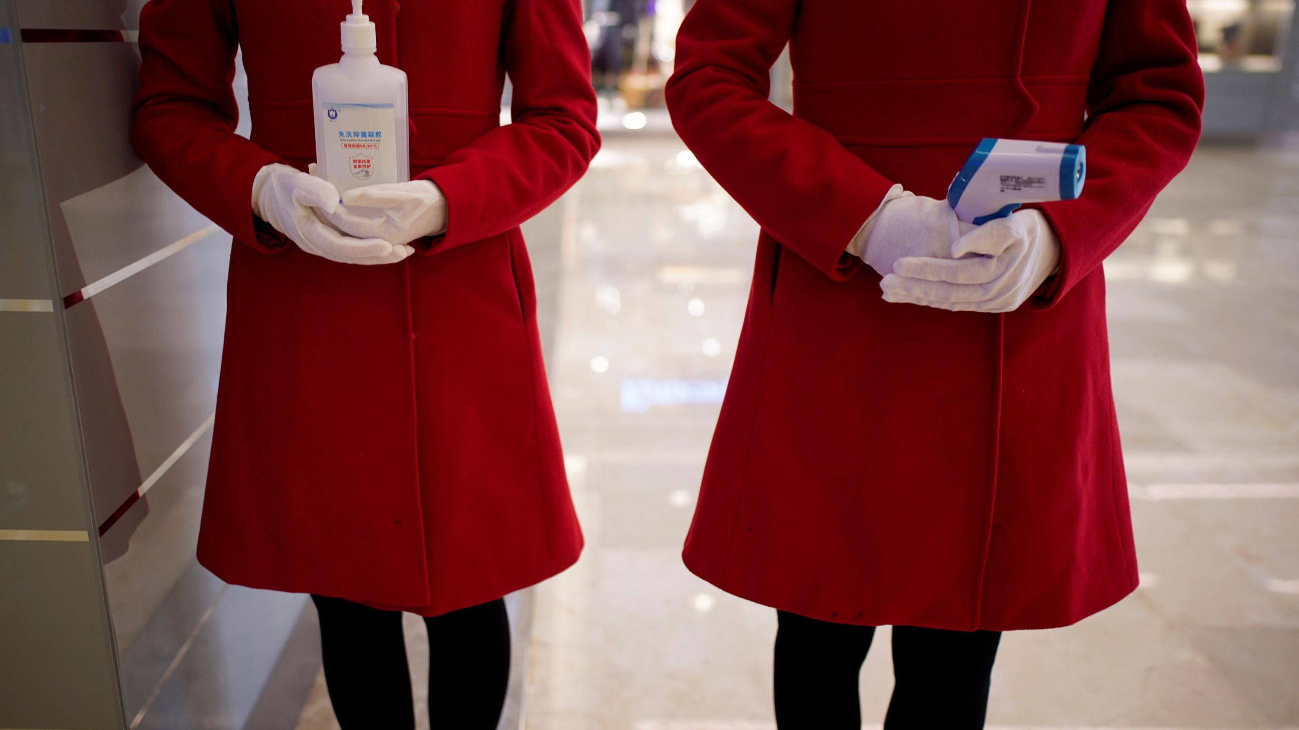 This is a striking photo of the torsos, waists and thighs of two women wearing brilliant red dresses standing at attention. 