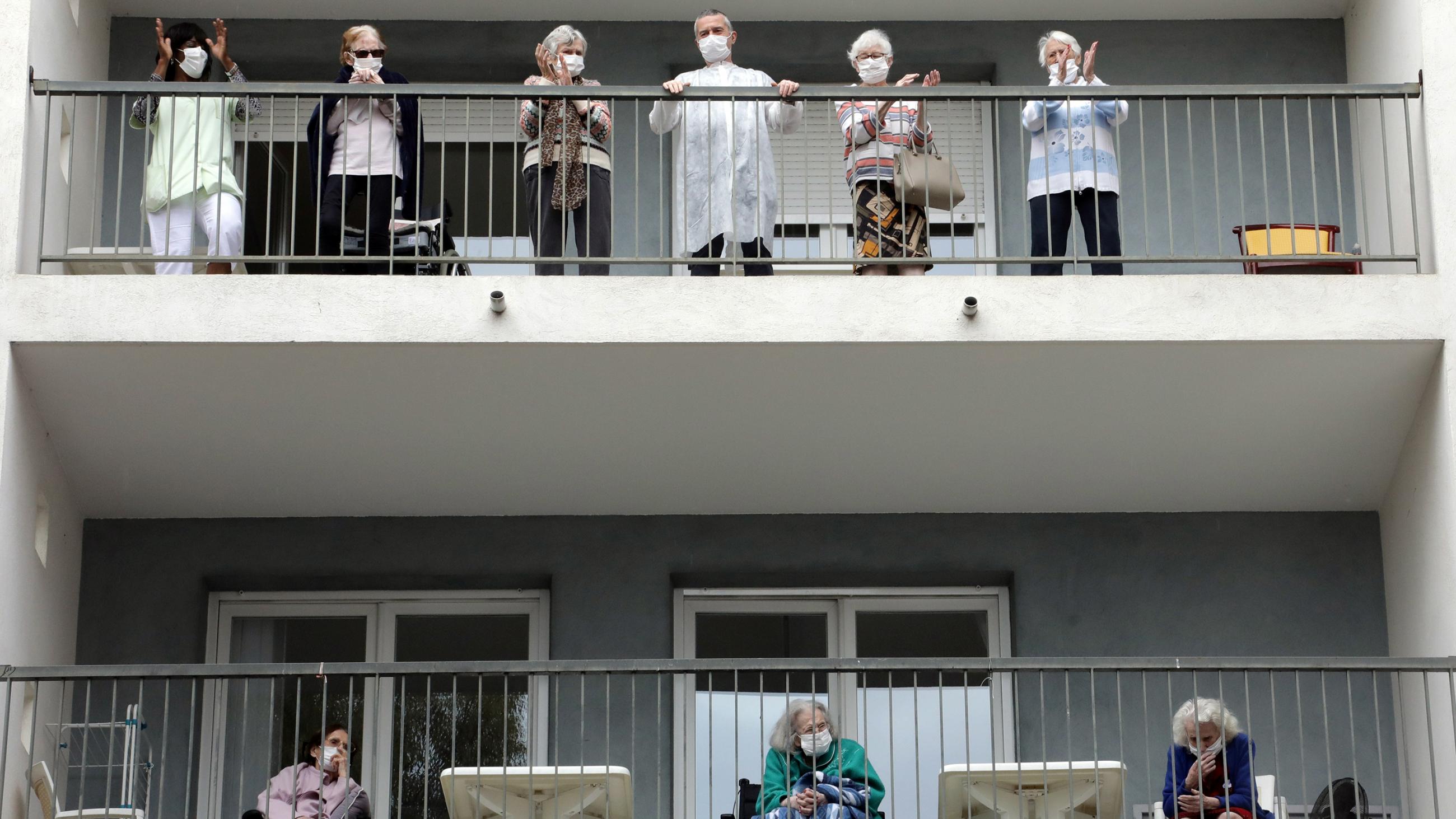 The photo shows two rows of balconies lined with elderly people watching the performance. 