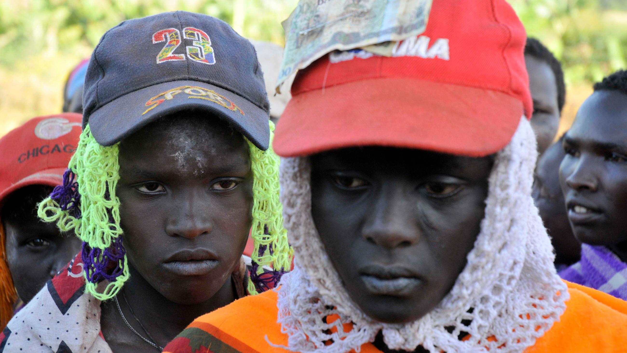 The photo shows a few young women wearing trucker hats and hair nets with somber looks on their faces.