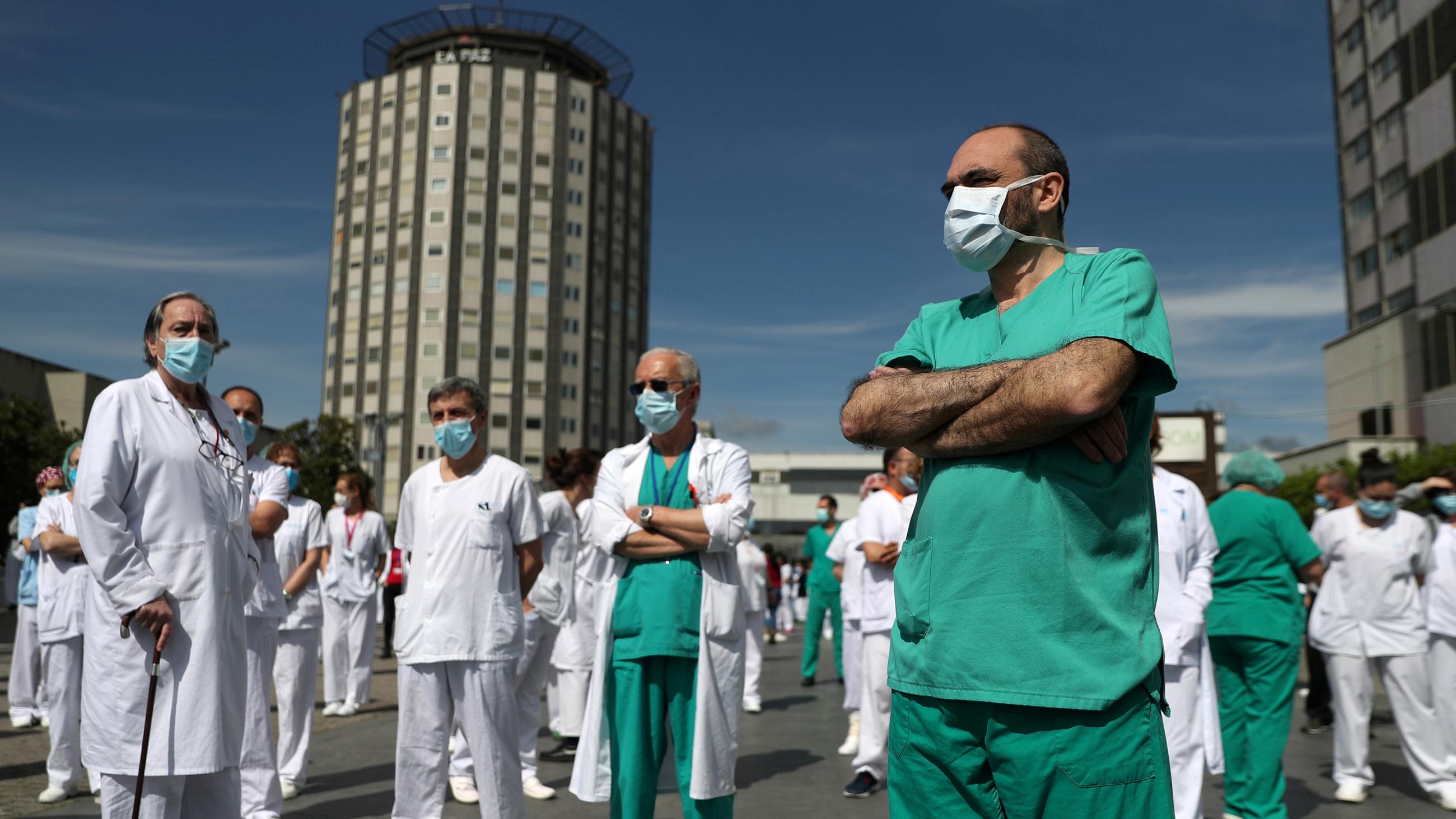 The photo shows a number of medical staff standing around in the bright, bright sunlight talking. 