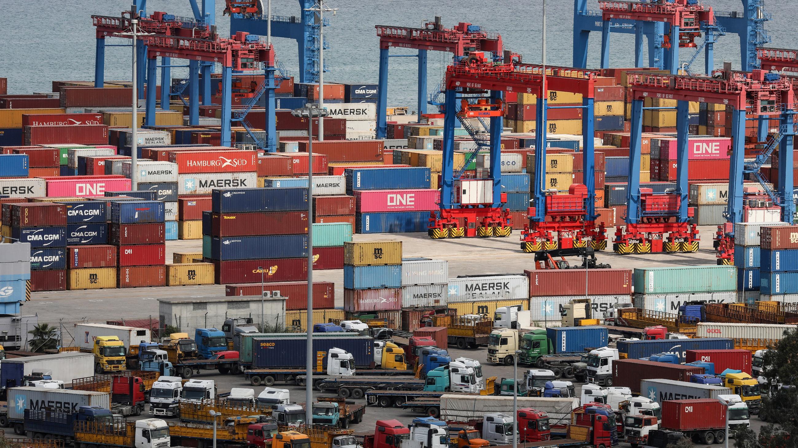 The photo shows an amazing pile of machines and metal containers stacked high, wall-to-wall in an overloaded industrial seaside dock. 