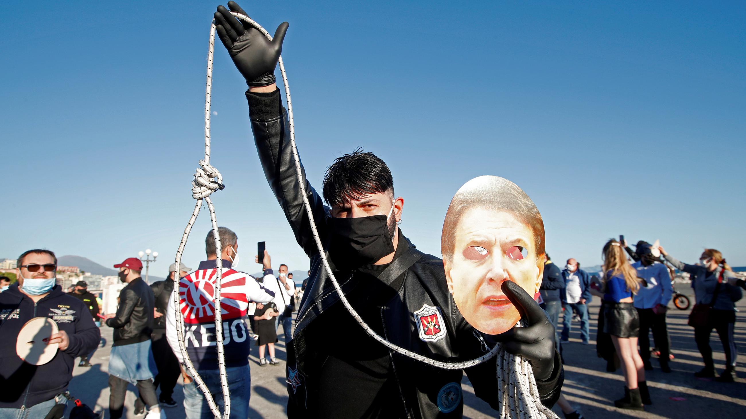 The photo shows a man with a mask brandishing a noose and a picture of the prime minister. 