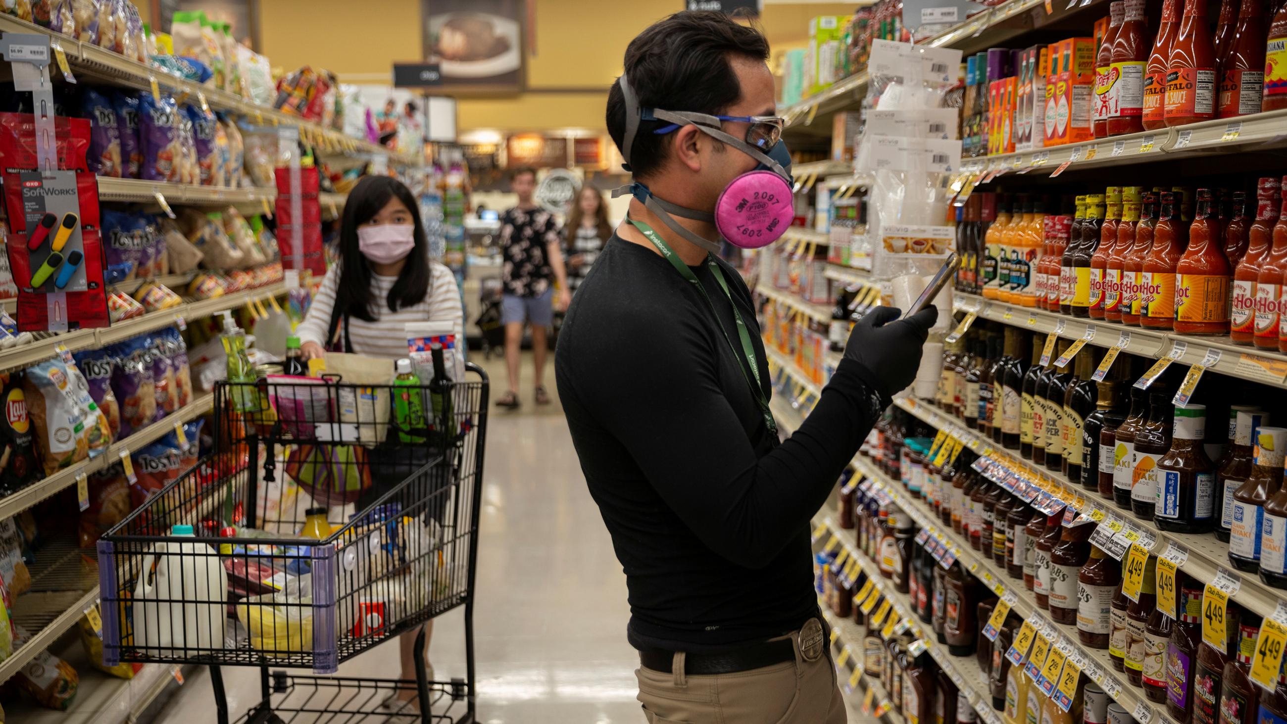 Picture shows Eric looking at a list standing amid canned goods in a grocery store. 