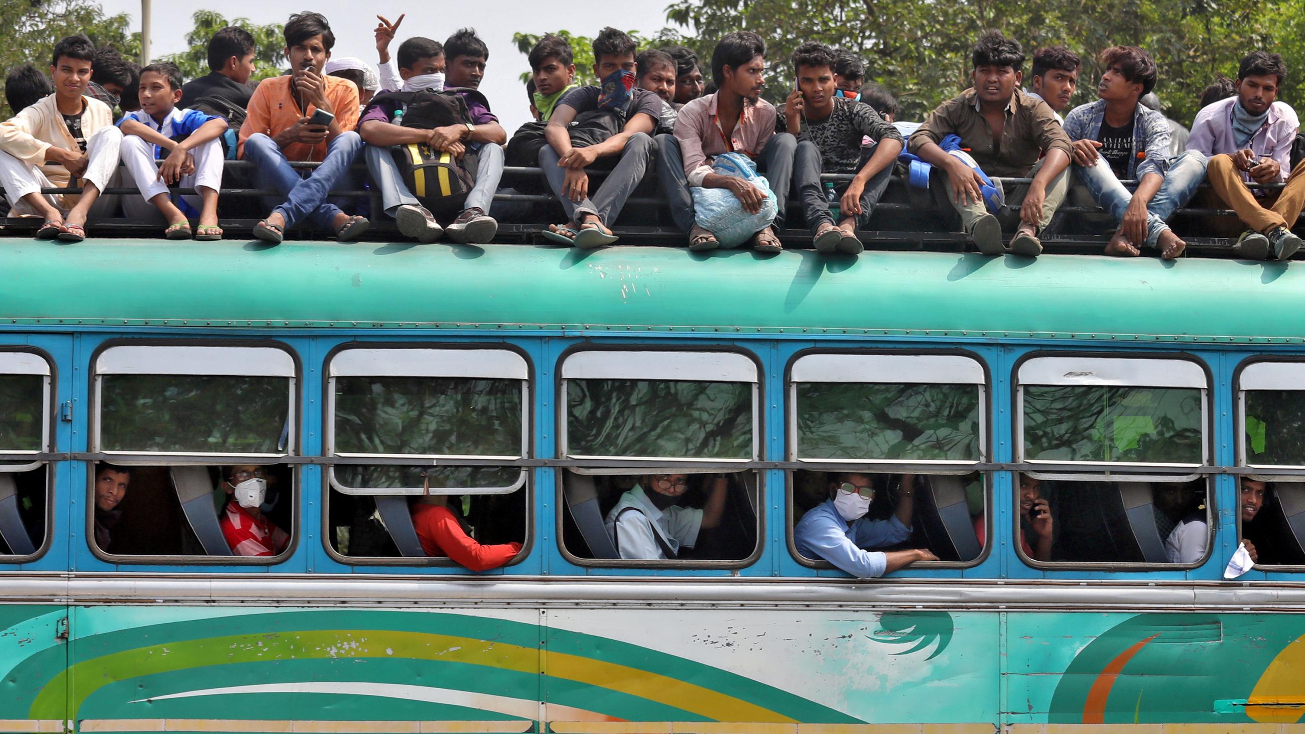 This is a stunning photo of a passenger bus with people sitting on top and in all the aisles inside. 