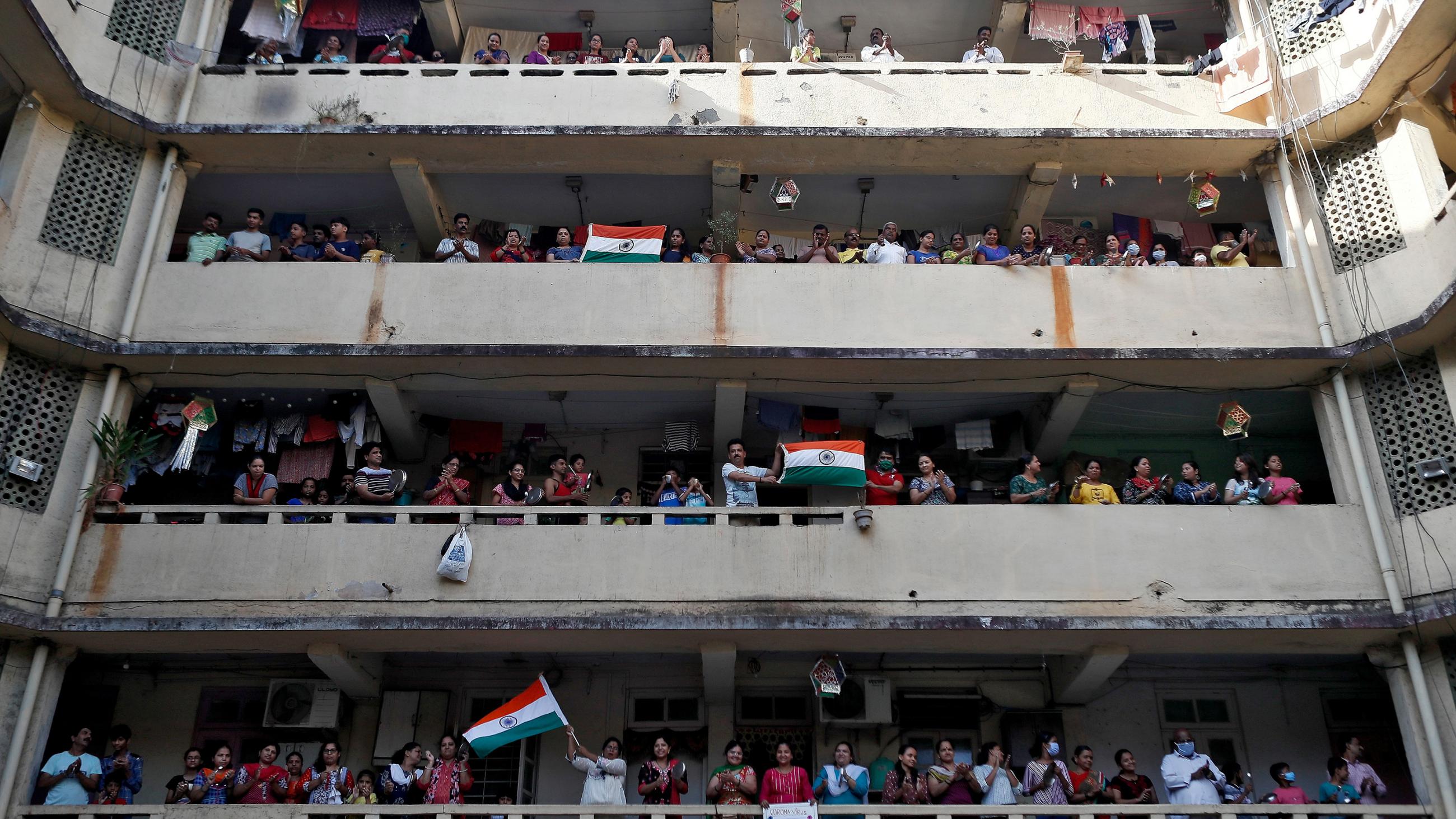 The photo shows three balconies of a large building filled with people cheering. 