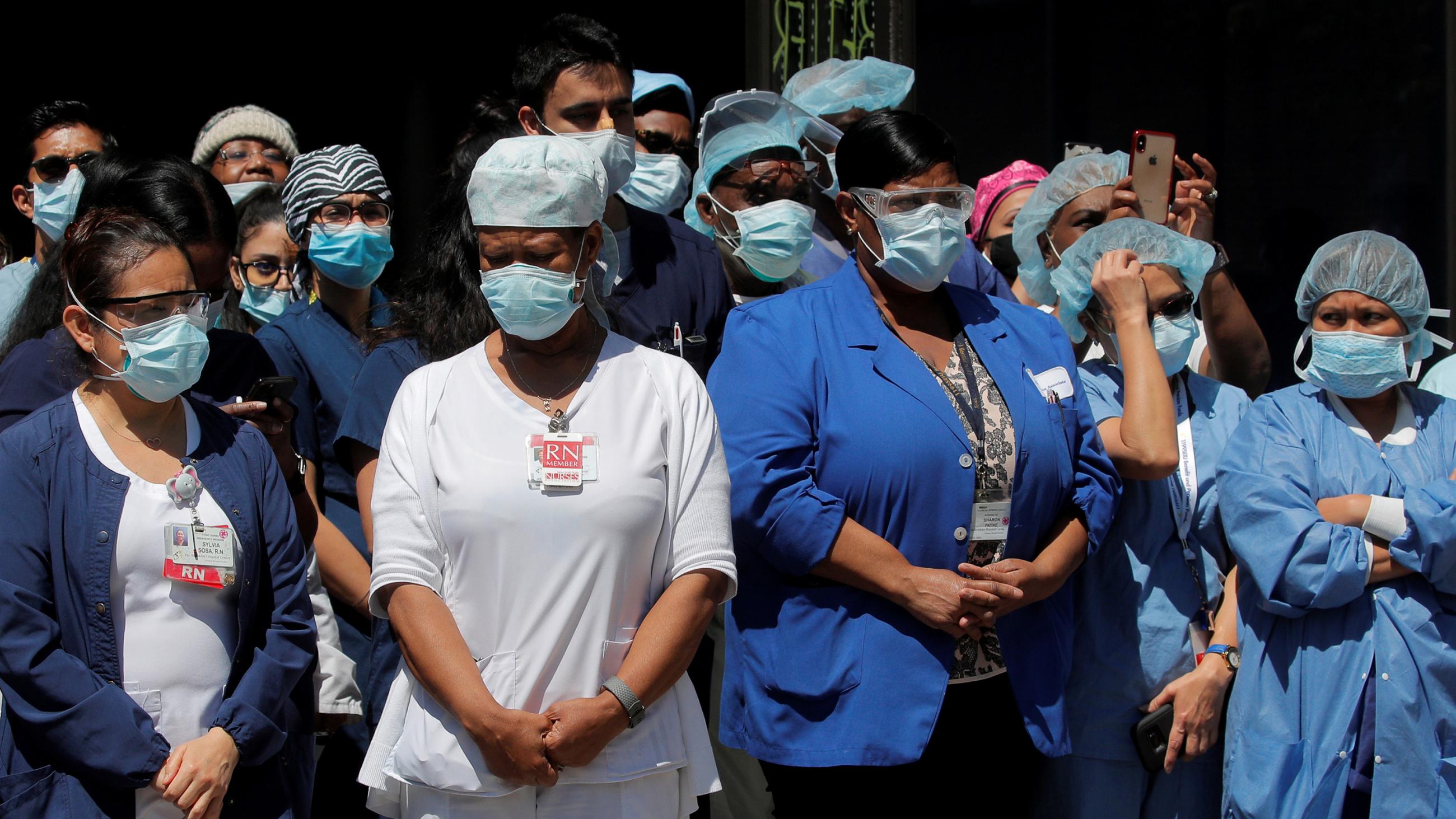 The photo shows a huge number of health workers standing quietly waiting. 