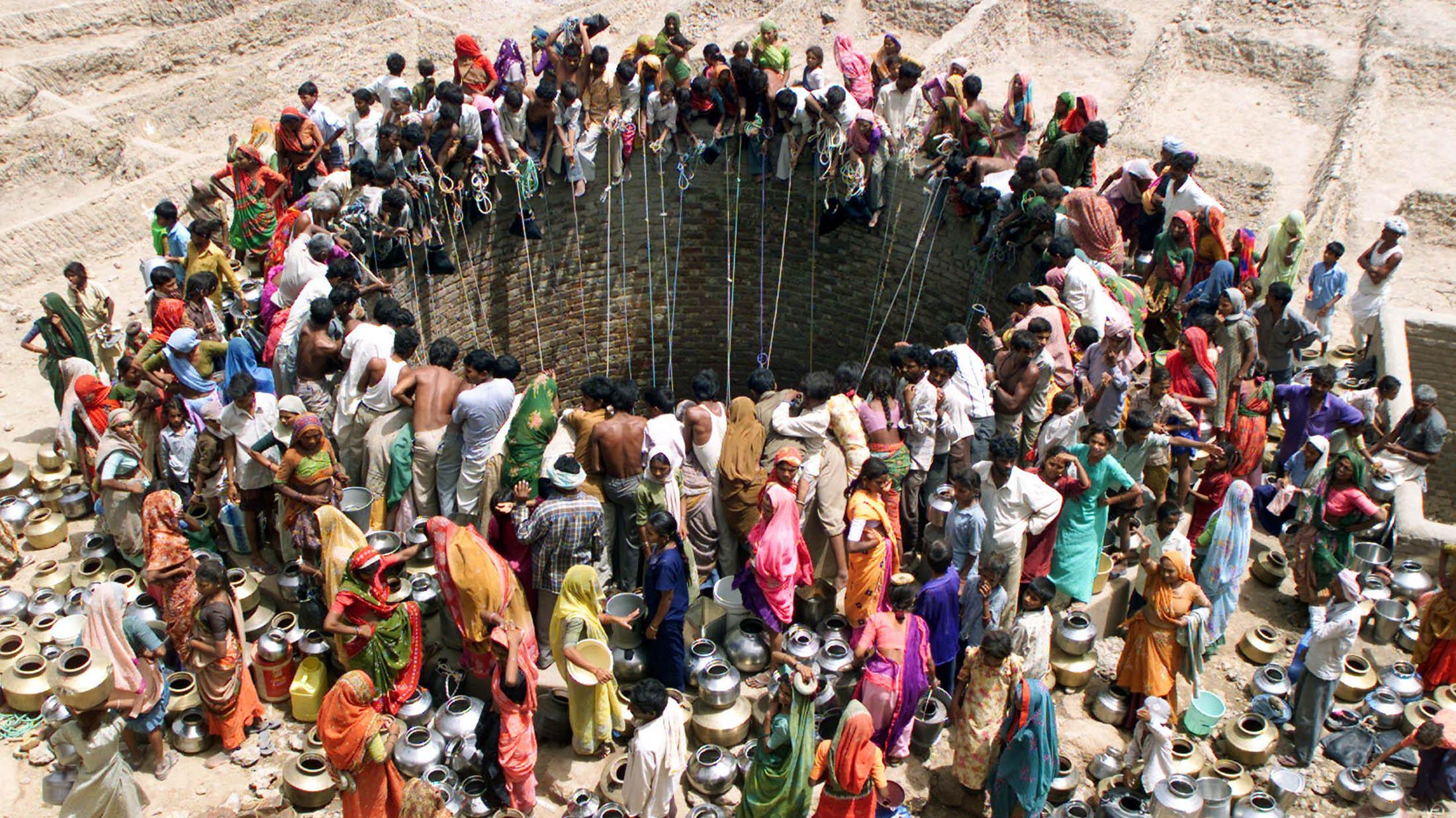 This is an iconic photo that shows a large number of people gathered around an open well. 