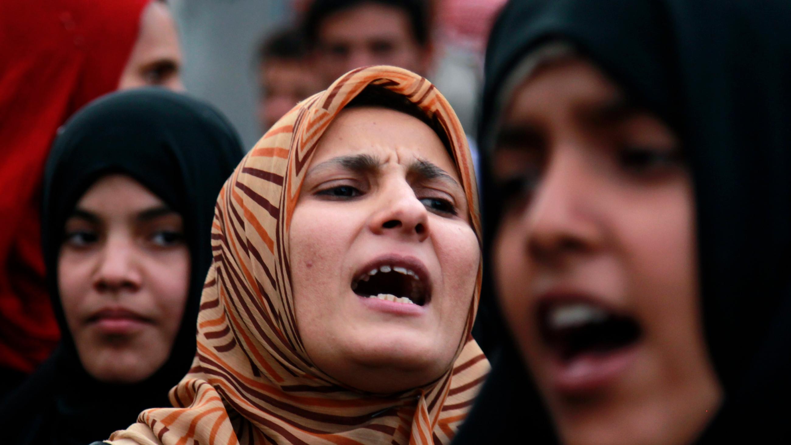 The photo shows a number of women in a crowd. Several are seen shouting.