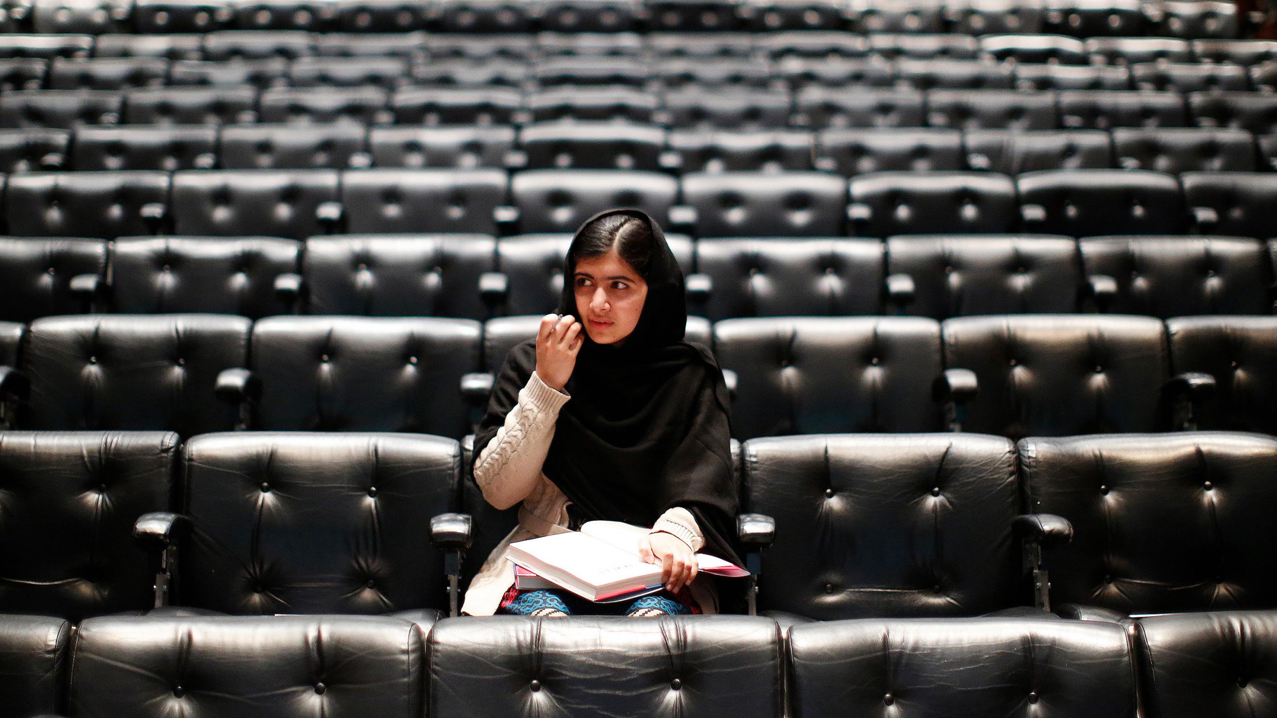 The photo shows Malala in an empty auditorium seated where the audience will sit to listen to her. 