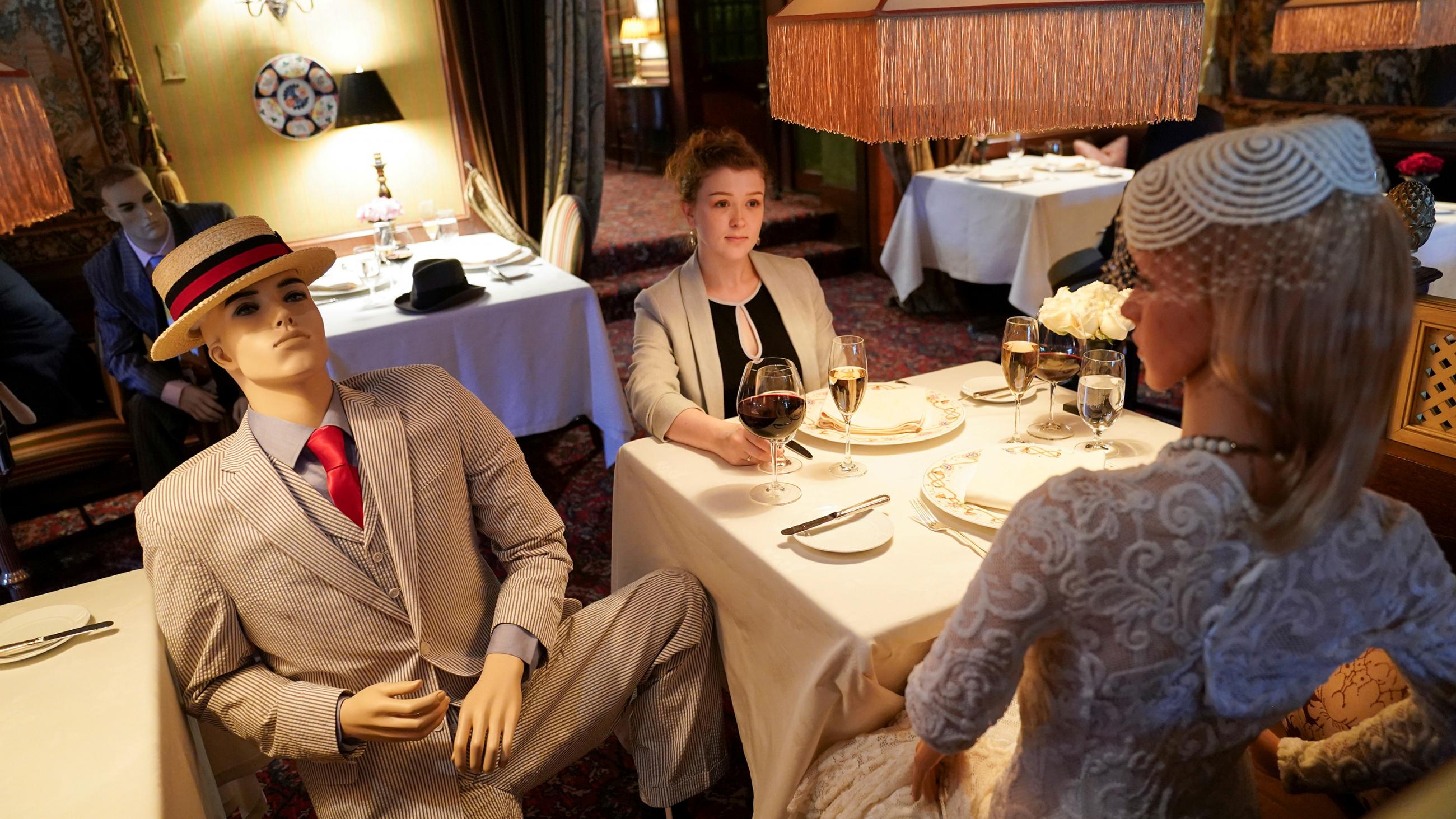 The photo shows a woman at a table with mannekins. 