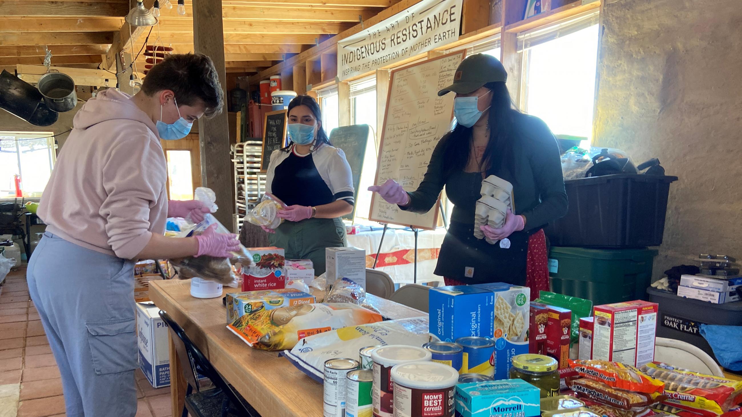 Picture shows several people around a long table overflowing with essential supplies.