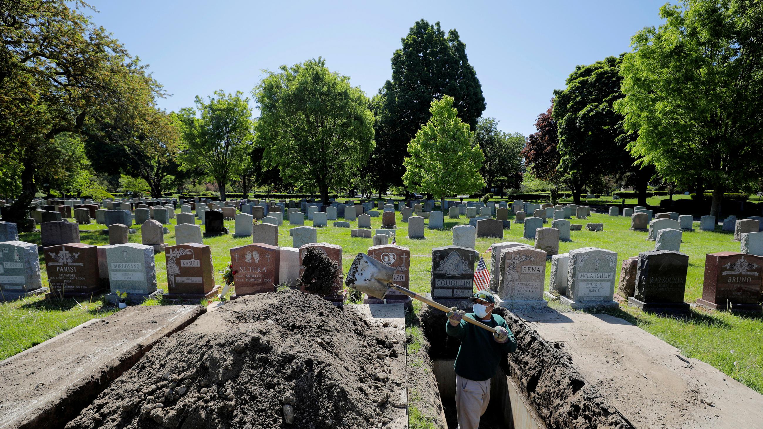 The image shows a cemetery with a grave freshly dug. 