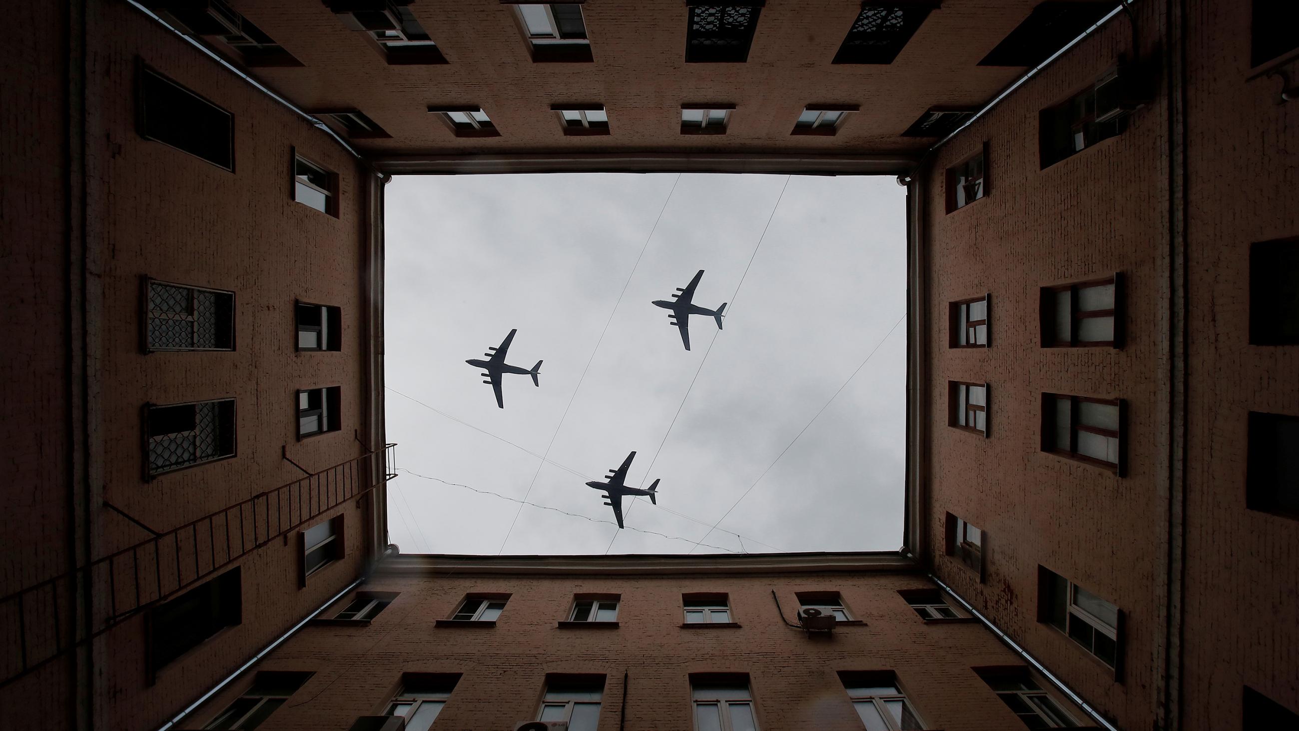 The striking image shows three planes photographed looking up througg the open courtyard of a large apartment-style building. 