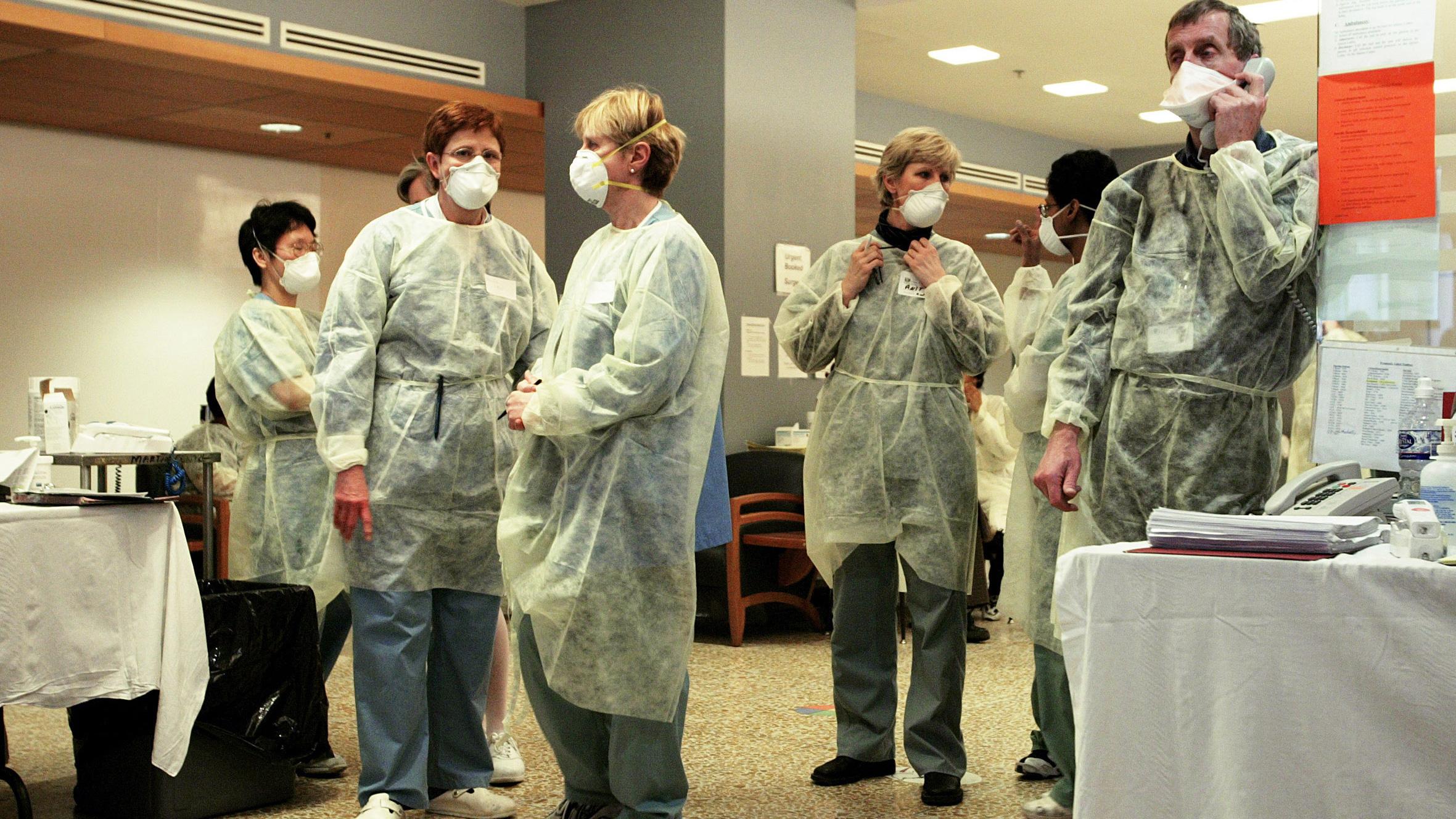 The photo shows a number of hospital staff waiting and talking amongst themselves. One is on the phone. 