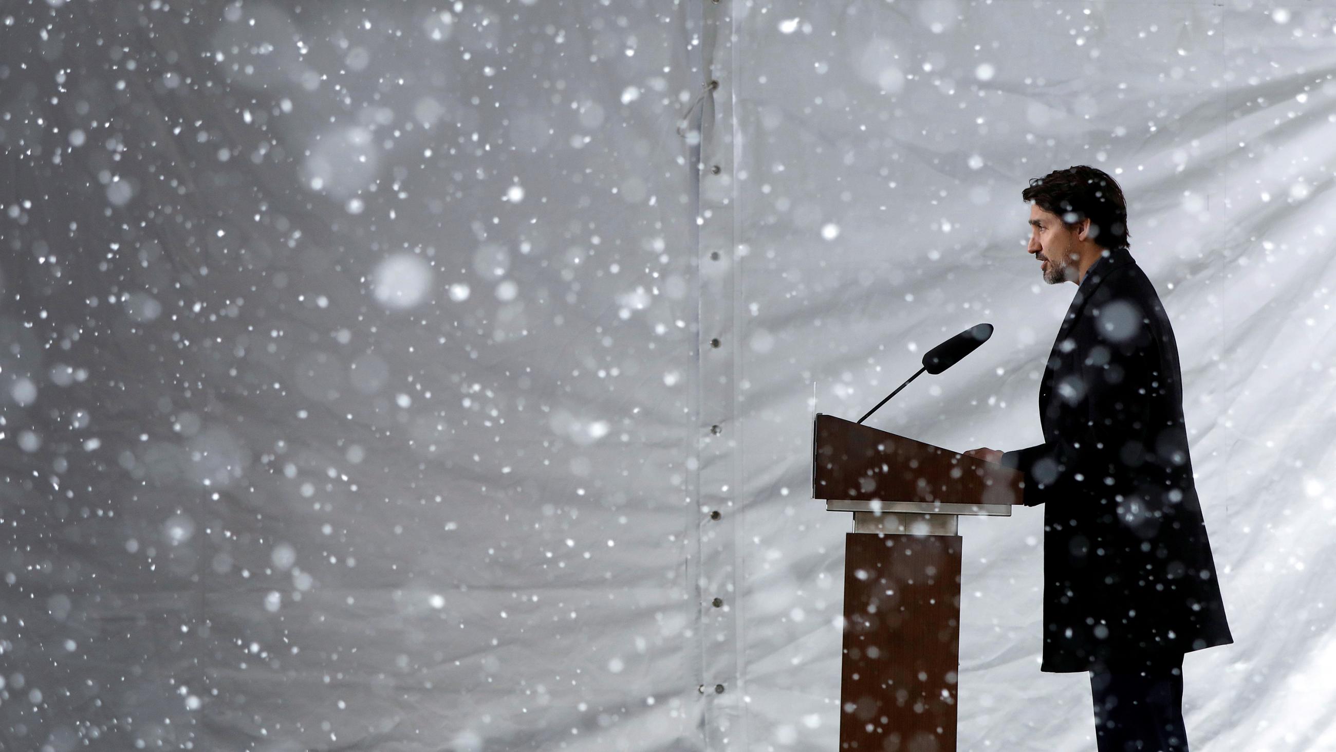 The photo shows the prime minister from the side standing at a podium while a driving snowstorm can be seen in the photo. 