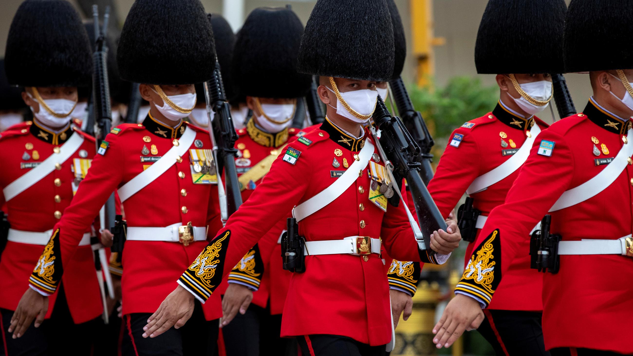 The photo shows the honor guard clad in bright red military coats on parade in lock step. 