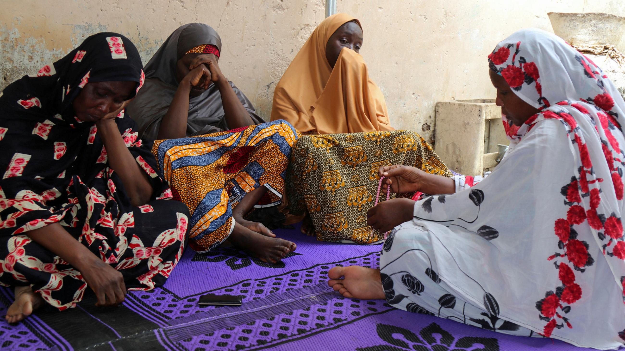 The photo shows several women sitting in mourning. 