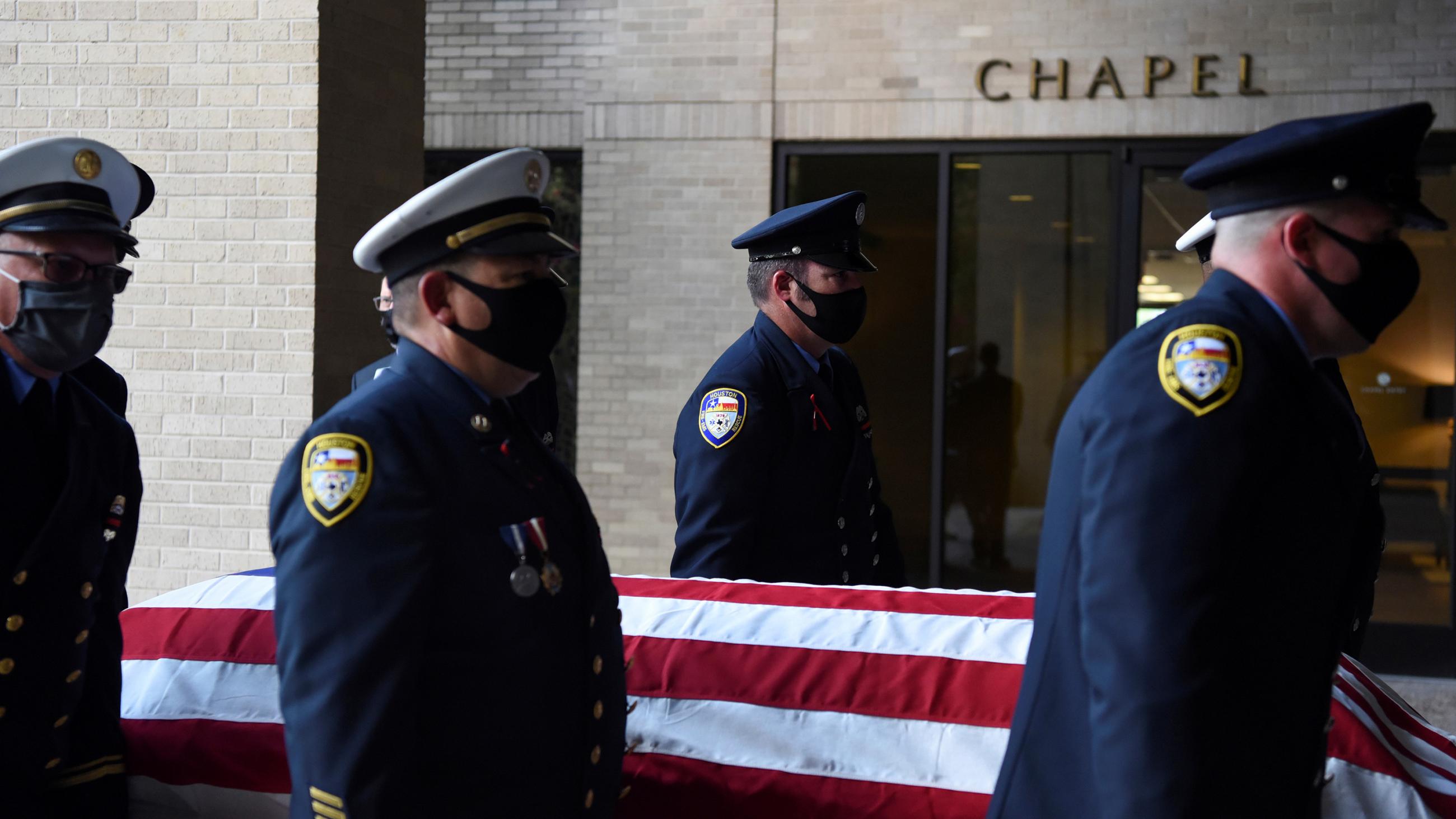 The photo shows a firefighter honor guard carrying a casket. 