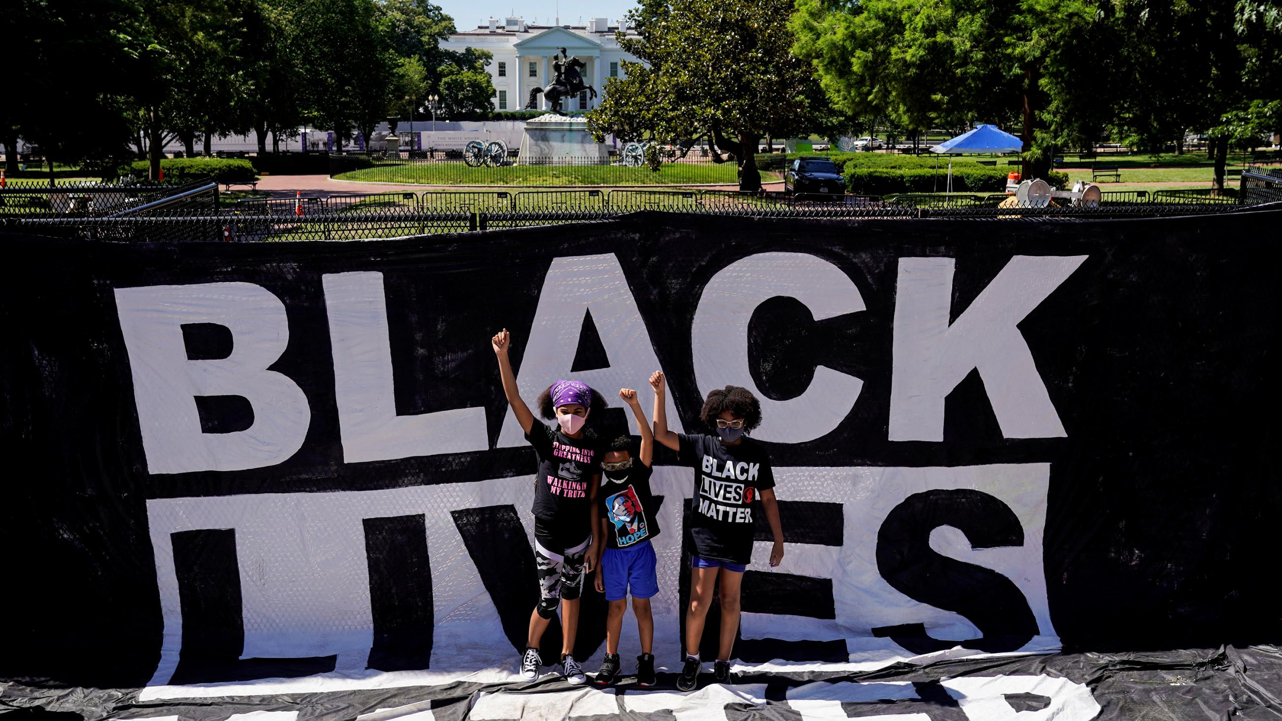 The photo shows a group of small children standing amid black lives matter signs. 