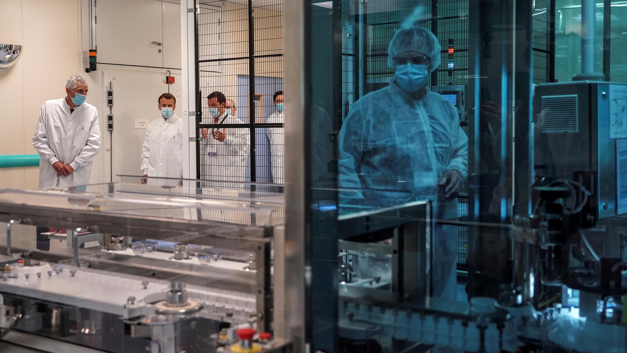 The photo shows the French president and an entourage in a high-tech biomedical facility 