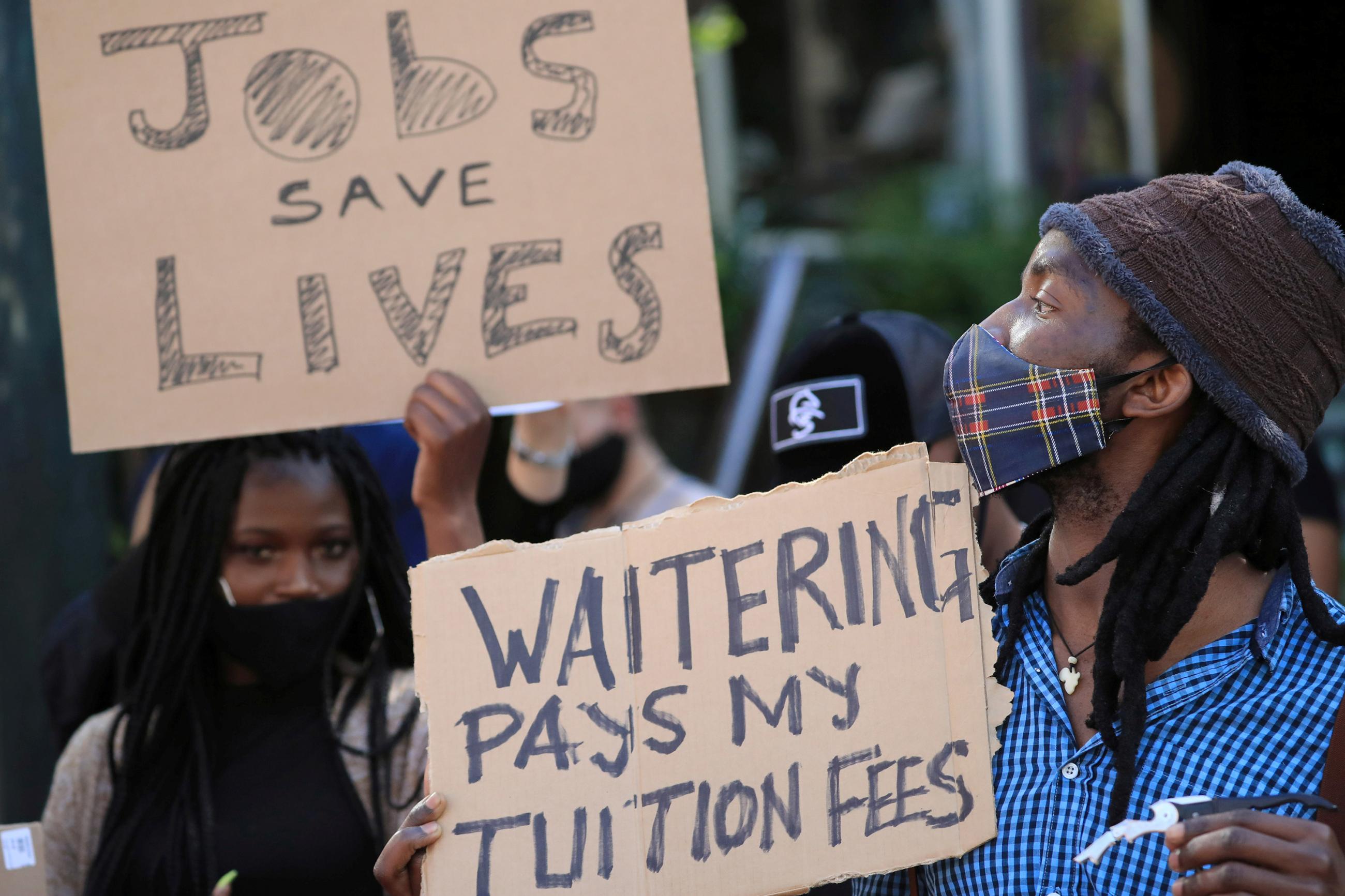 The photo shows protesting workers with handmade signs.