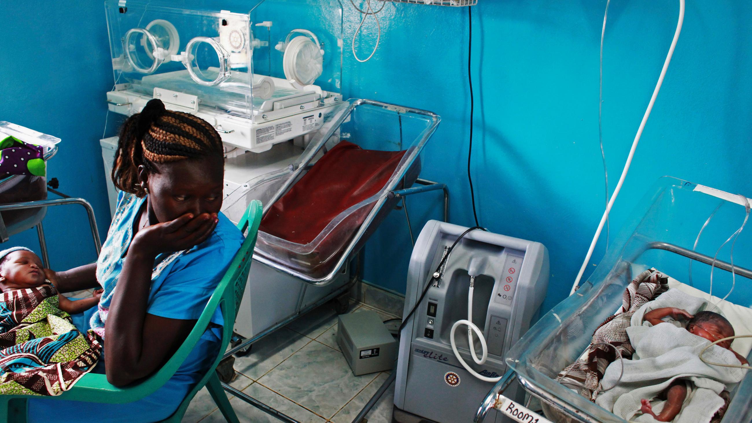 The photo shows the woman looking back at her baby, who is sleeping in a small hospital bed. 
