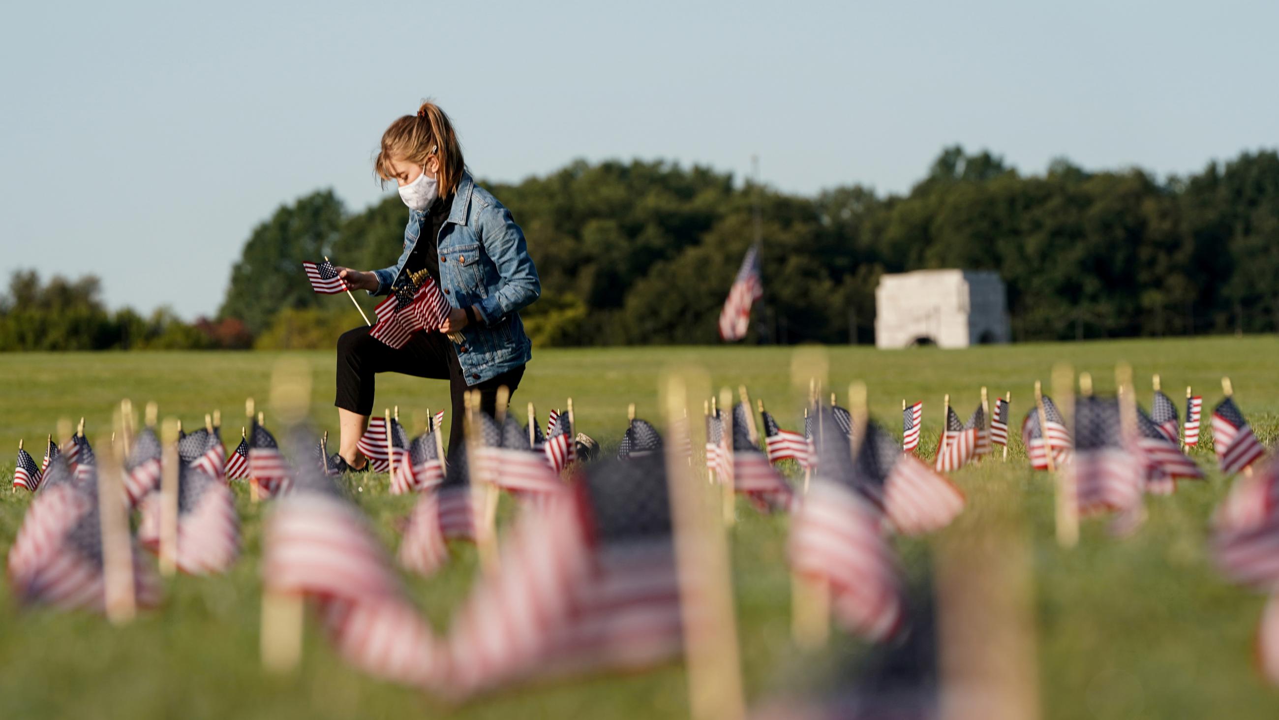 A volunteer places U.S. flags representing the 200,000 American lives lost during the COVID-19 pandemic in Washington, DC, on September 22, 2020.