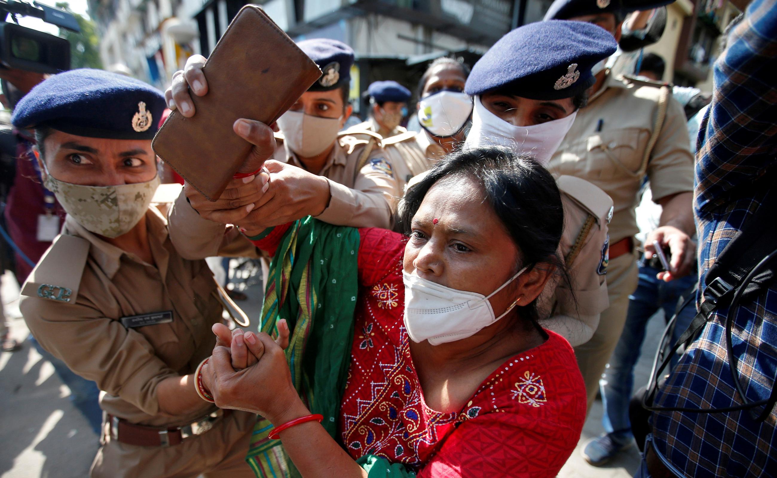 The photo shows a woman being led away by uniformed officers, who are grabbing her hands. 